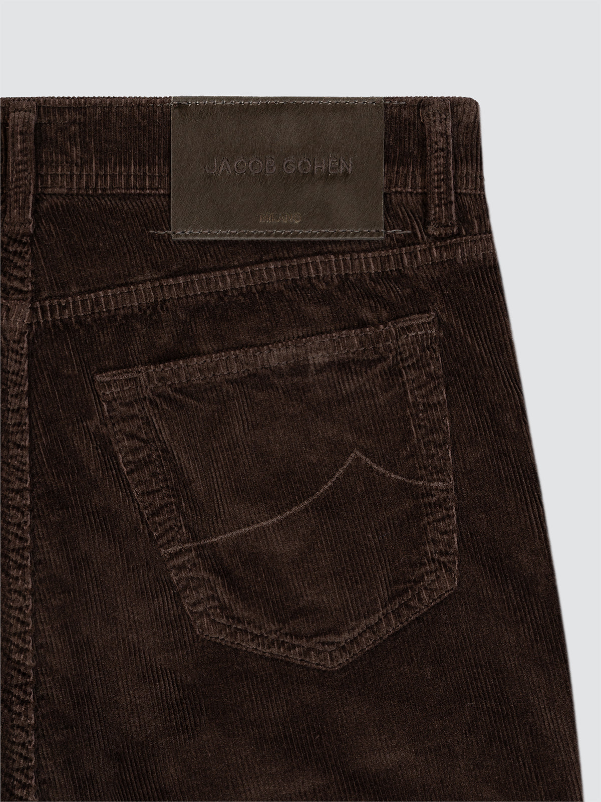 Close-up of brown corduroy pants 5 Pockets with a visible brand label on a light gray background