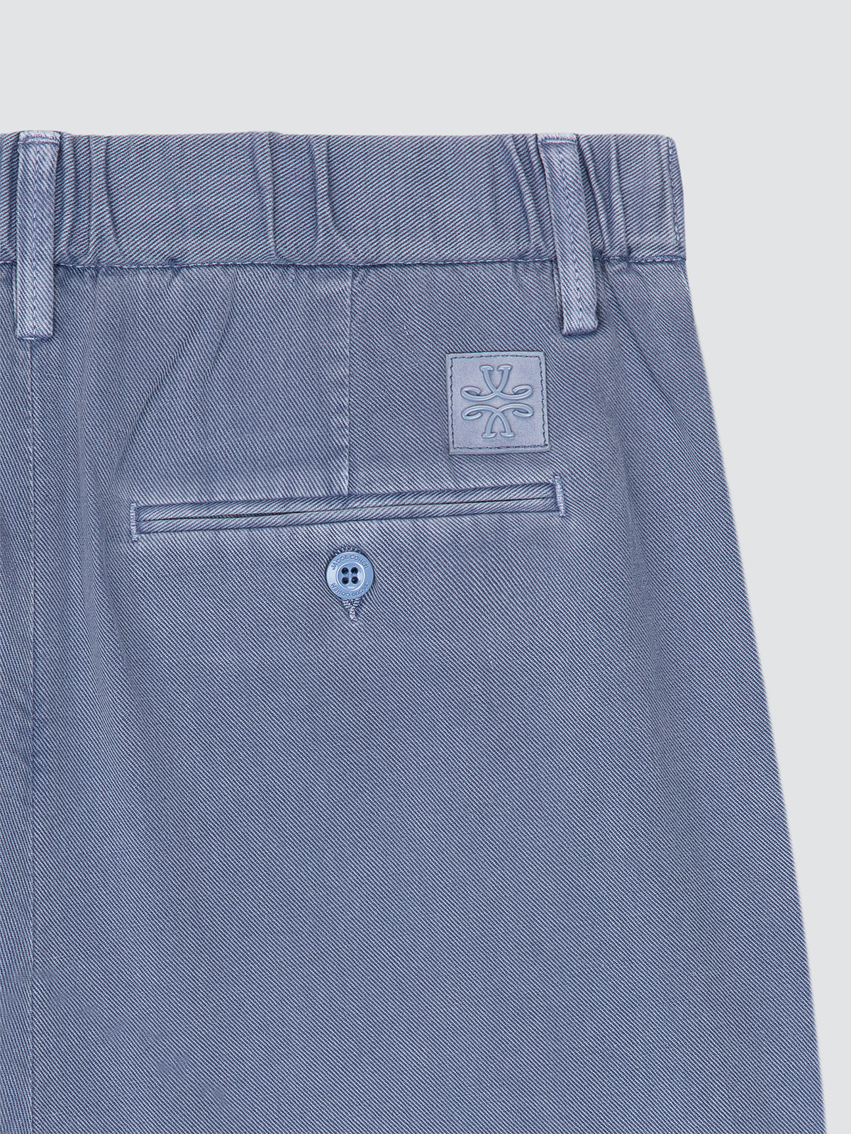 Close-up of a blue short with a brand logo Jacob Cohen on a light gray background
