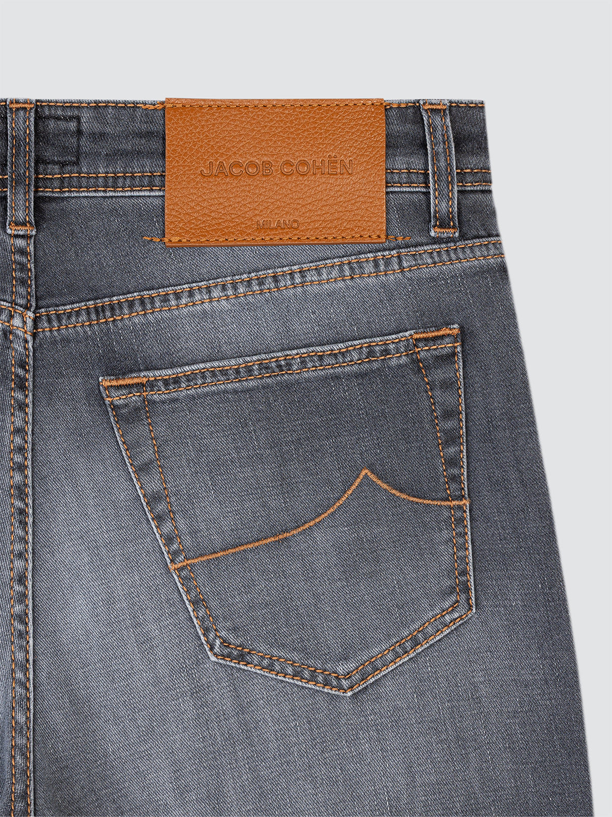 Close-up of a pair of jeans with a Jacob Cohen label on a gray background