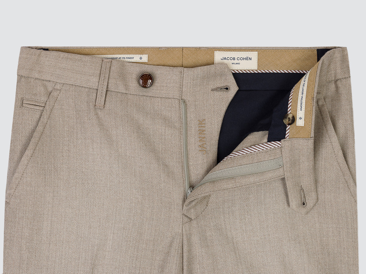 Close-up of a pair of light beige textured trousers by Jacob Cohen, showing the front waistband, button closure, belt loops, and an open right pocket revealing a navy blue inner lining.