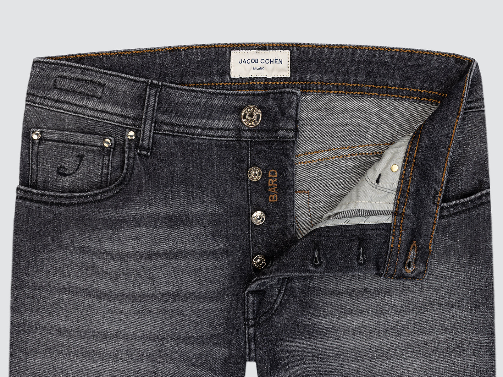 Close-up of black jeans with visible brand label on a light gray background