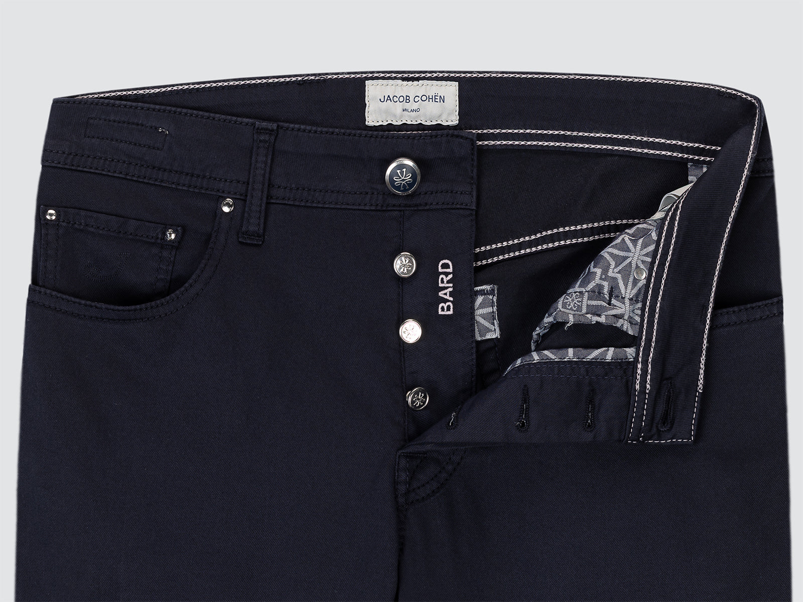 Close-up of black pants with visible branding on a light gray background