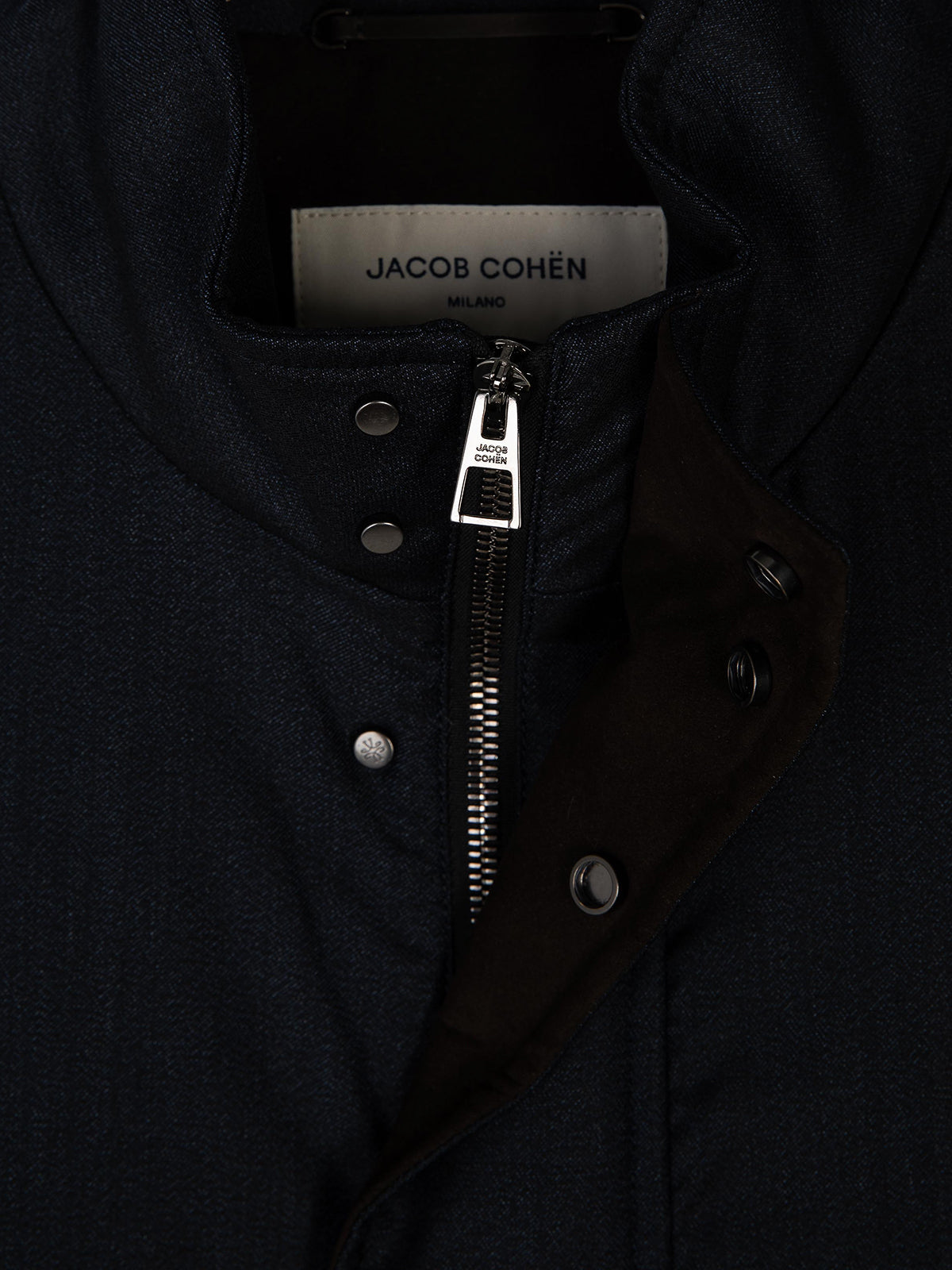 Close-up of a dark navy jacket by Jacob Cohen, showing the inner collar label, a silver zipper, snap buttons, and a dark brown inner lining.