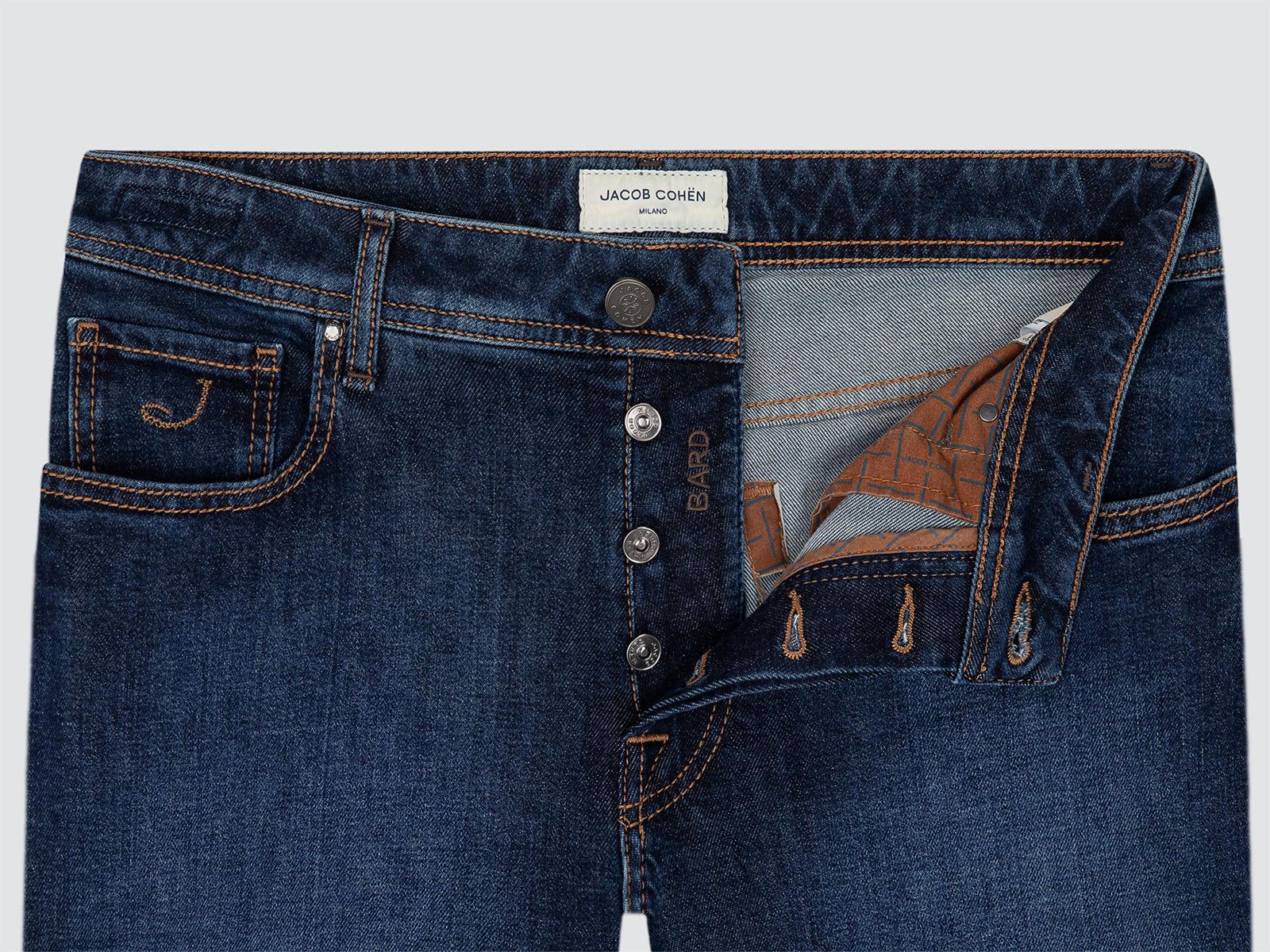 Close-up of a pair of dark blue denim jeans by Jacob Cohen, showing the front button closure, pocket detail, and interior lining.