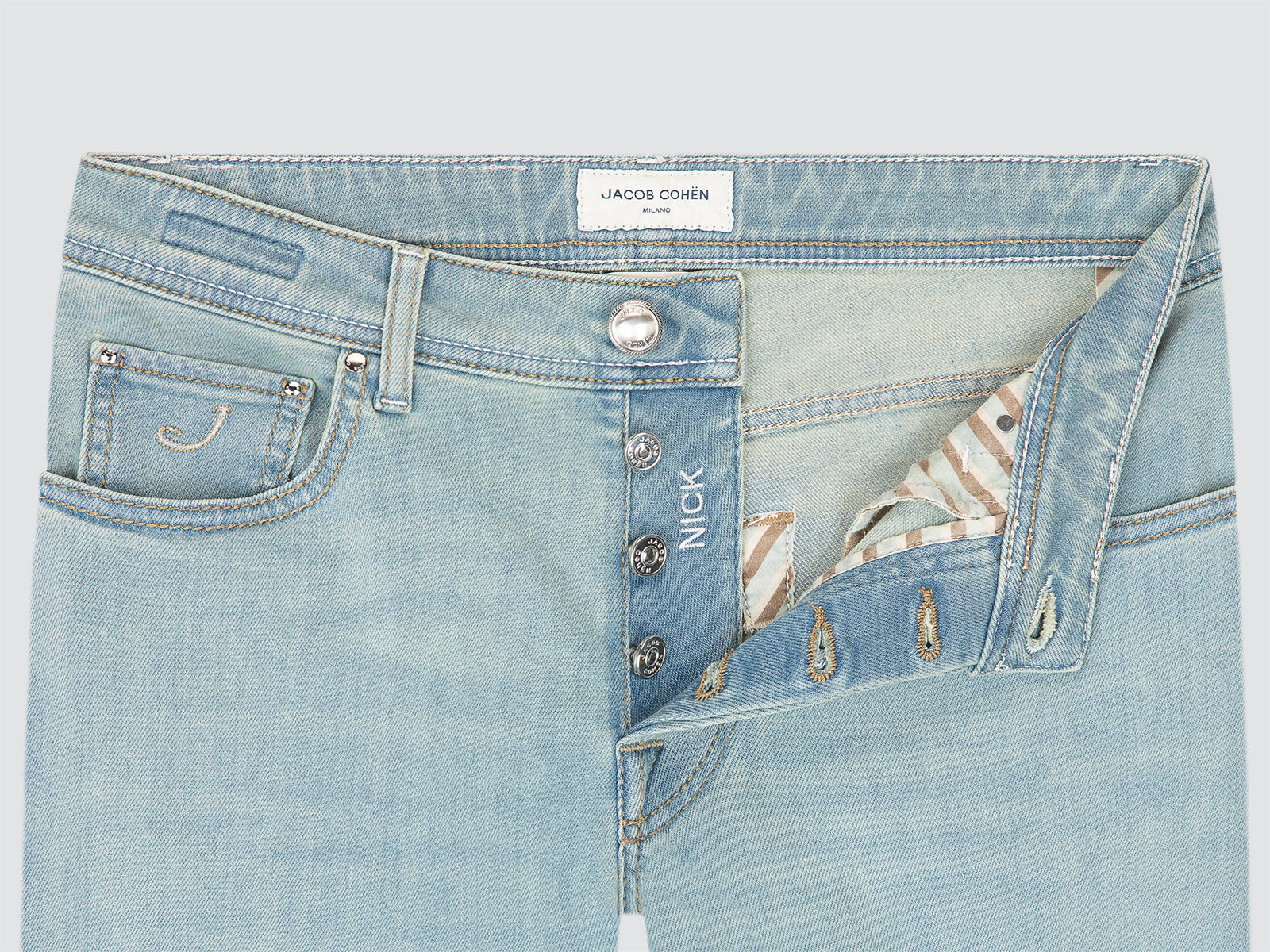 Light blue denim jeans with brand labels on a light gray background