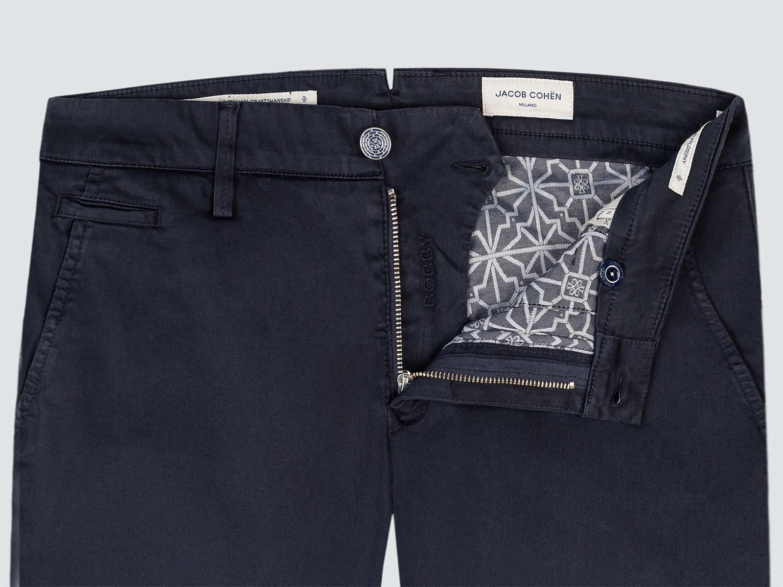 Black pants with a patterned lining and Jacob Cohen label on a light gray background