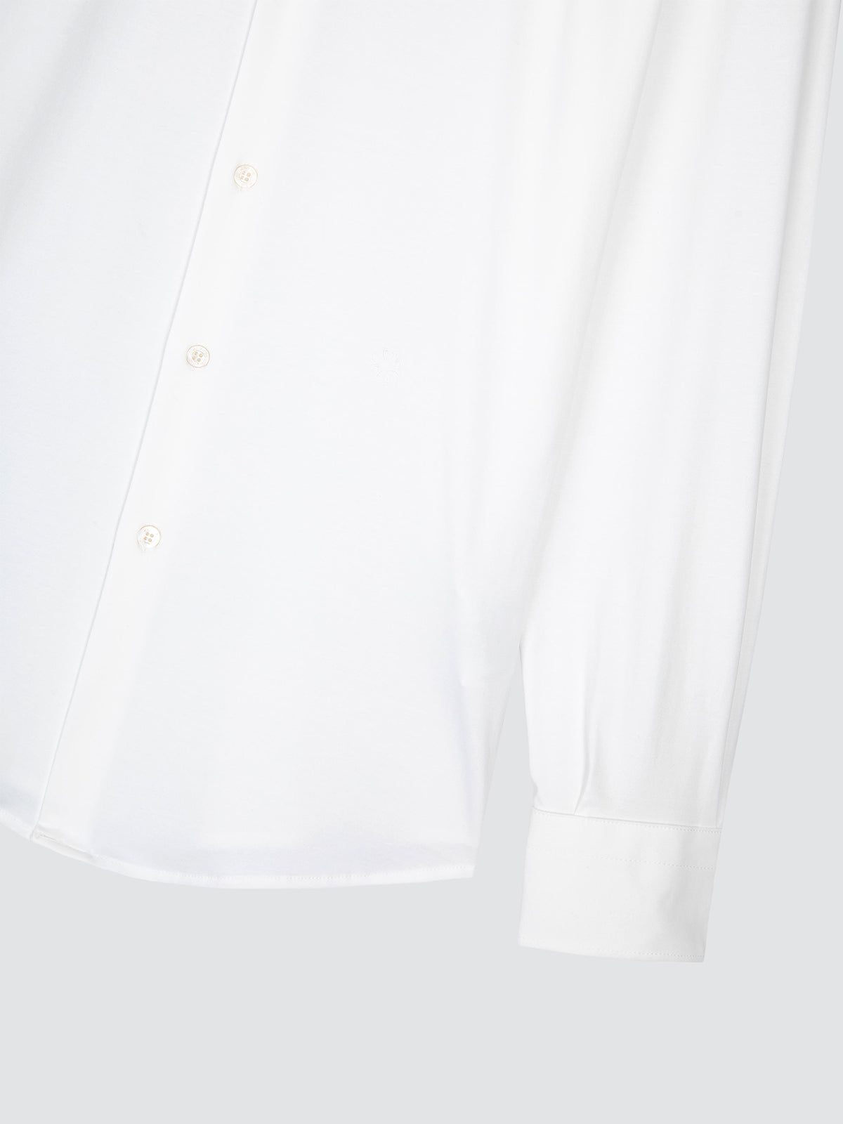 Close-up of a white long-sleeve button-up shirt showing the front placket and cuff on a light gray background.