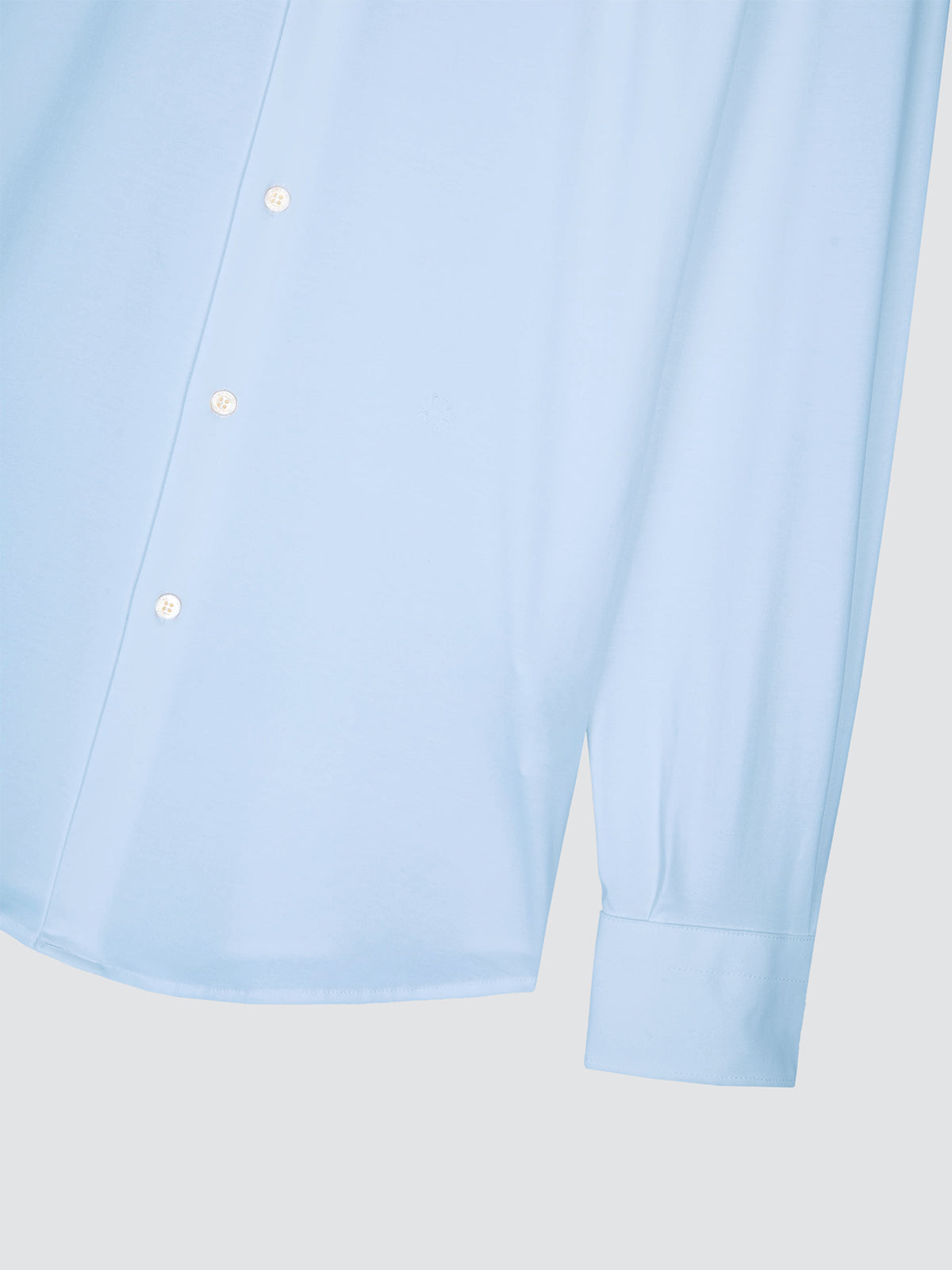 Close-up of a light blue long-sleeve button-up shirt showing the front placket and cuff on a light gray background.