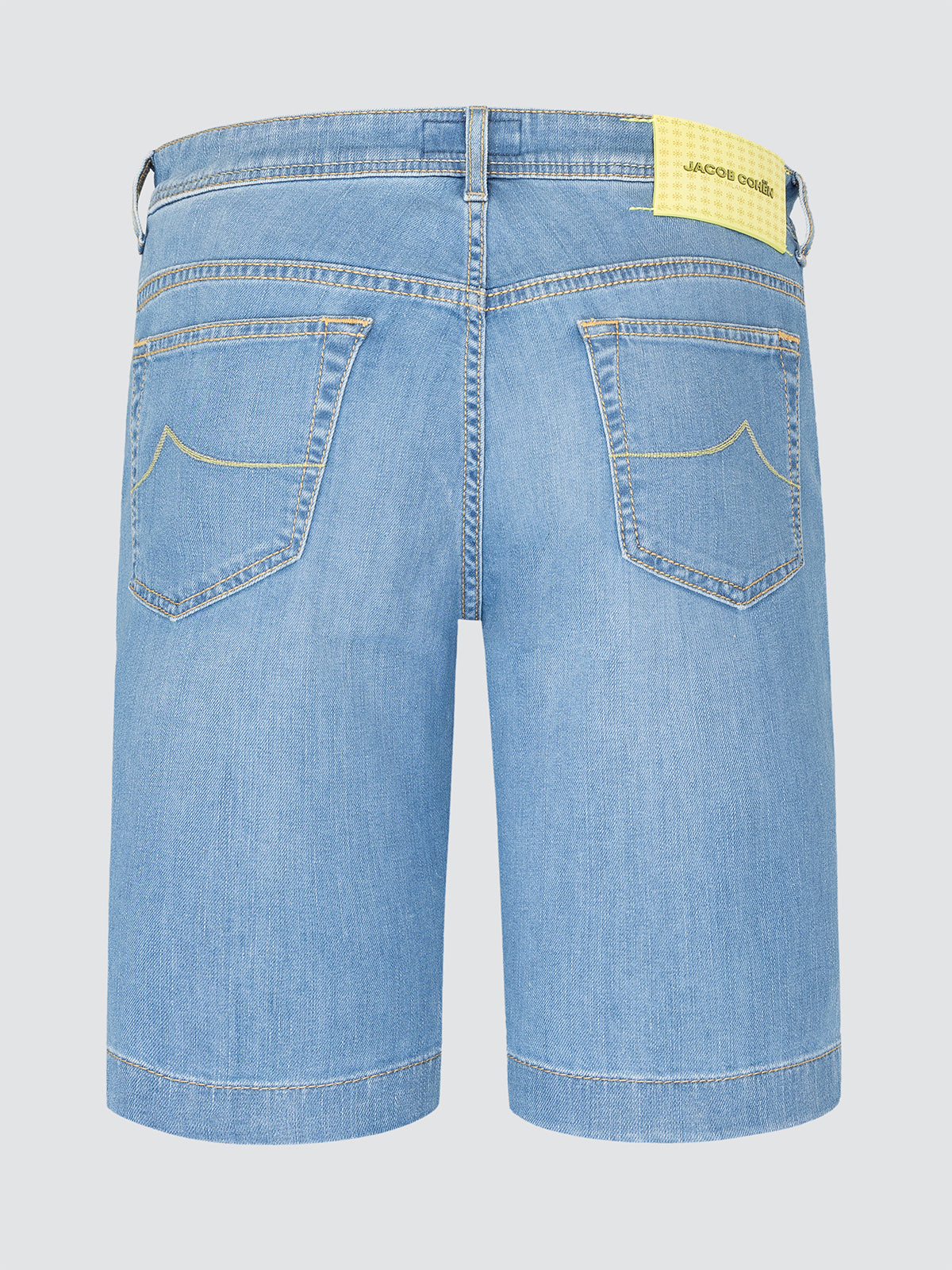 Blue denim shorts with a yellow patch on a light gray background