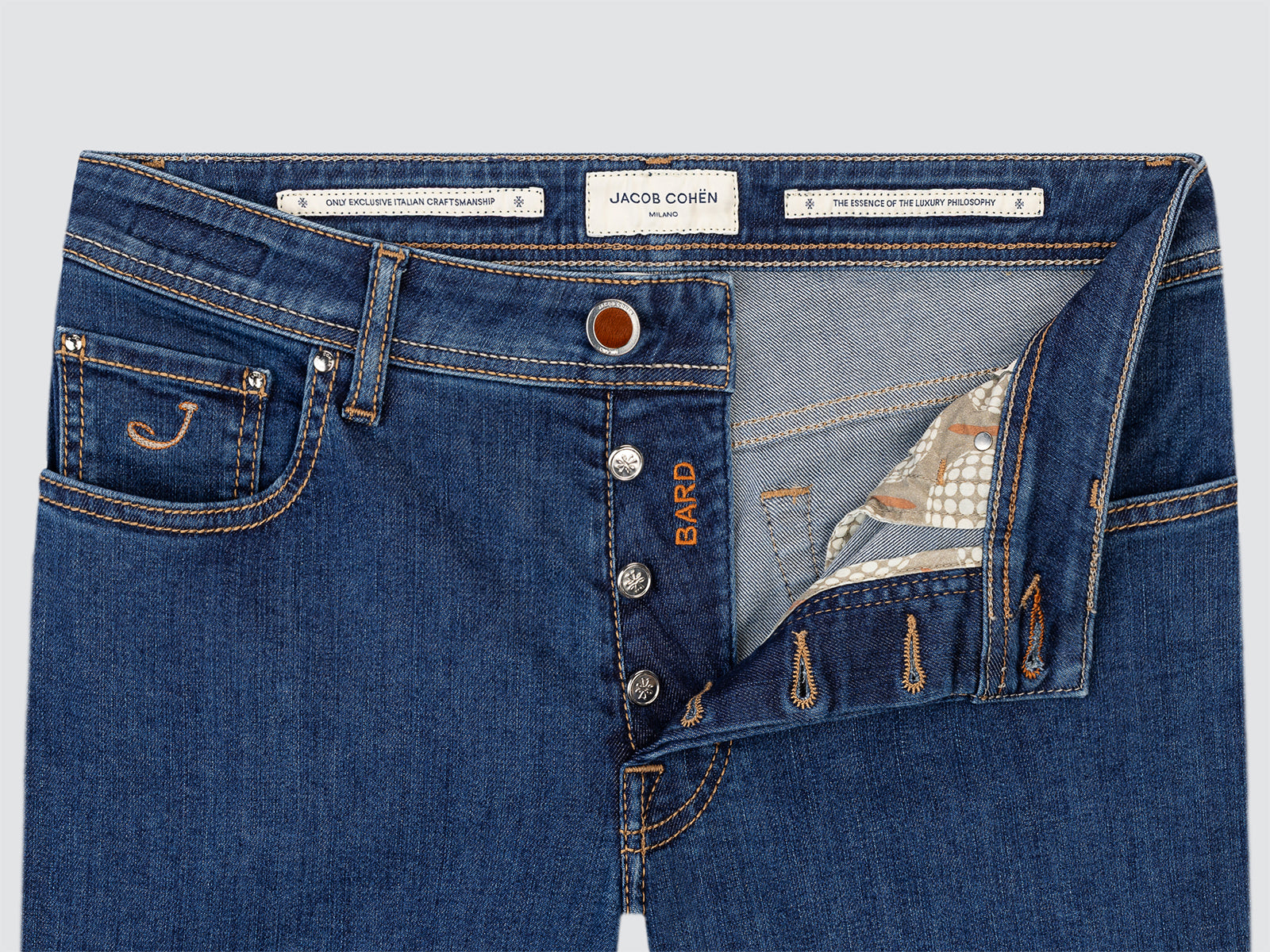 Close-up of blue jeans with brand labels on a light gray background