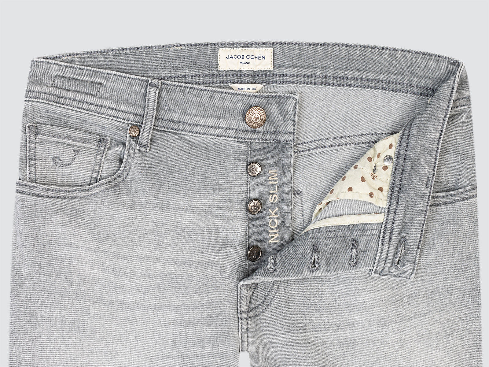 Close-up of gray jeans with brand label and button details on a light gray background