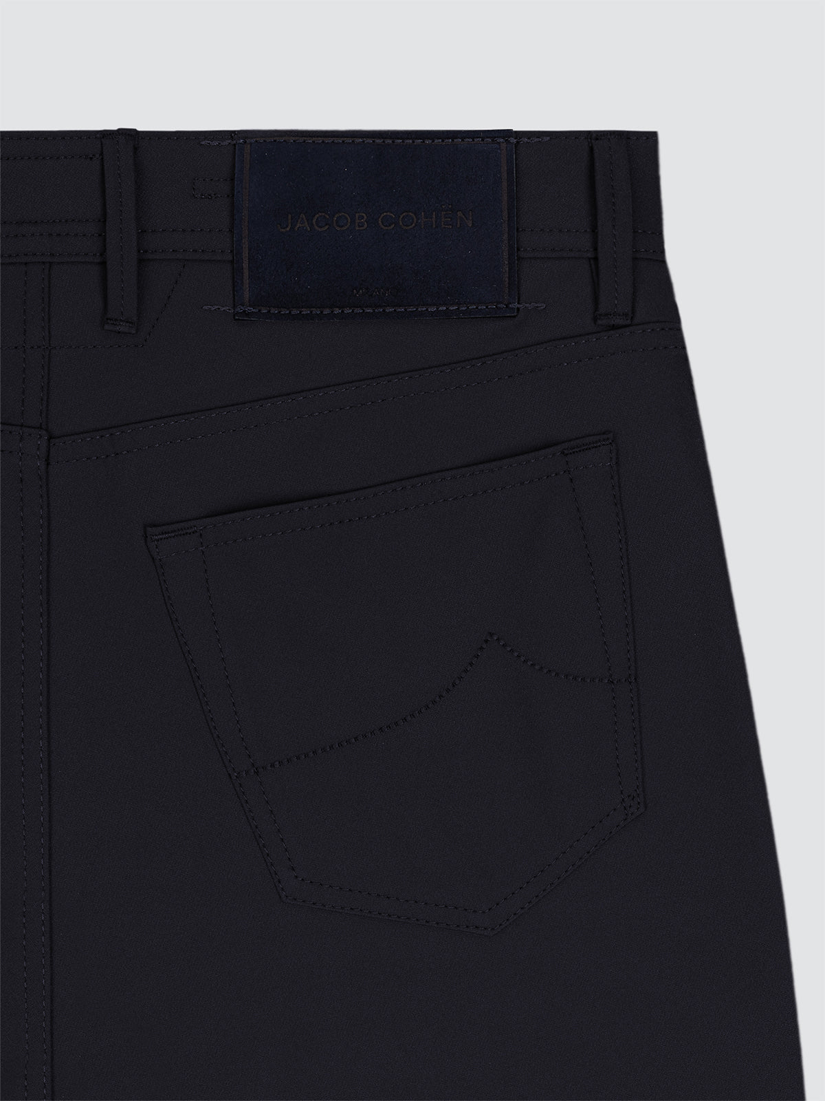 Close-up of Navy blue microfibre 5 pockets pants with a brand label on a light gray background