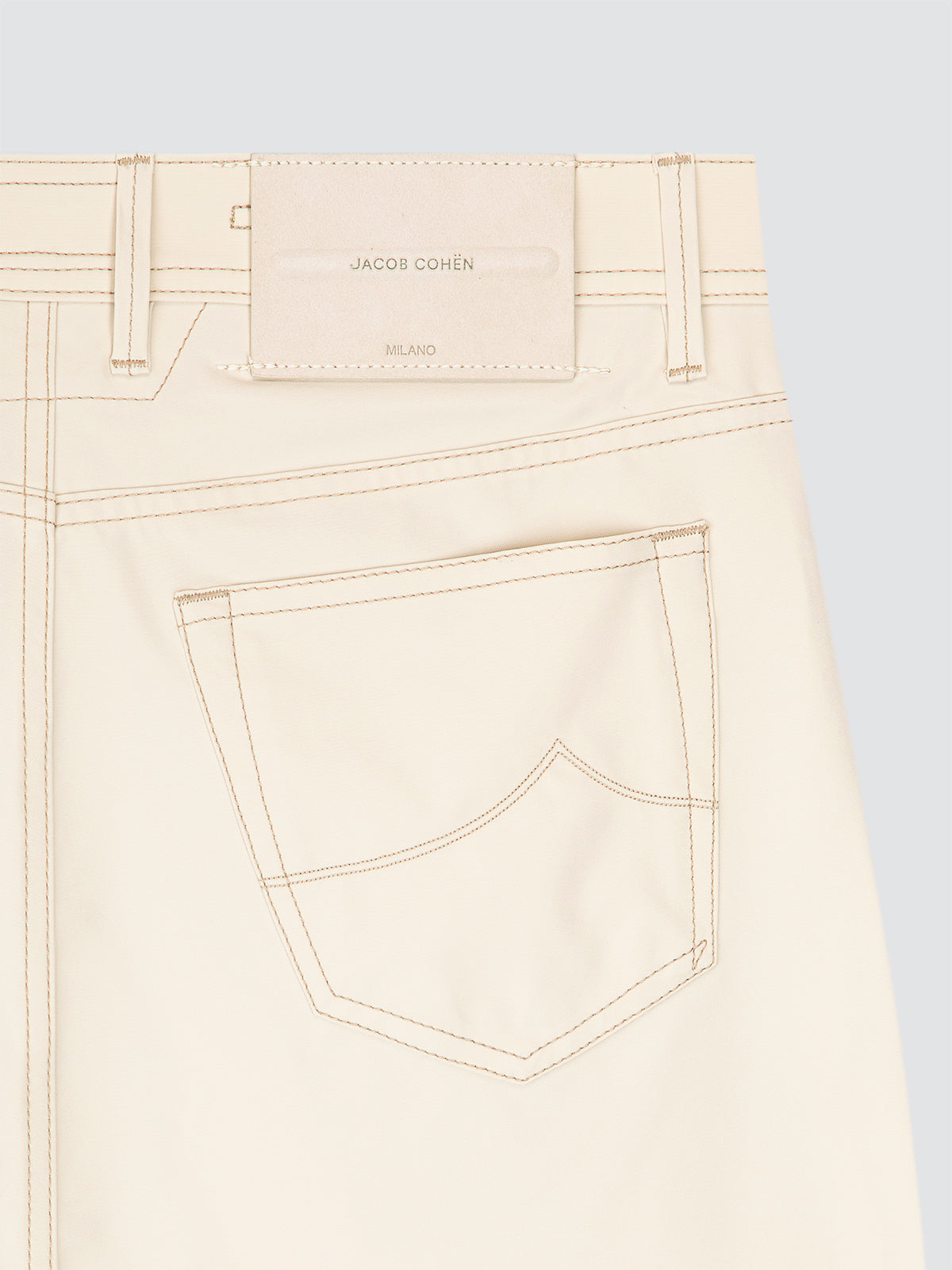 Close-up of beige pants traveller microfibre with a brand label Jacob Cohen on a grey background