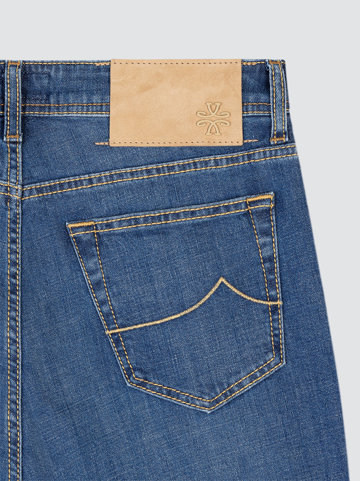 Close-up of blue jeans with a brand label on a light gray background