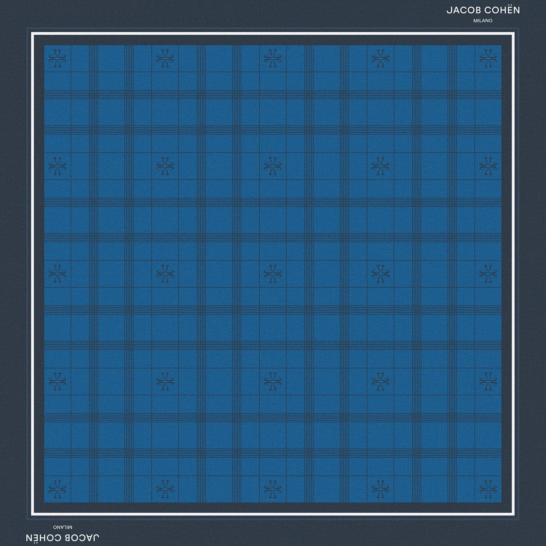 A square bandana featuring a blue and navy tartan plaid pattern, framed by a dark navy border with white text reading 'JACOB COHEN MILANO' at the top and bottom, set against a solid beige background.