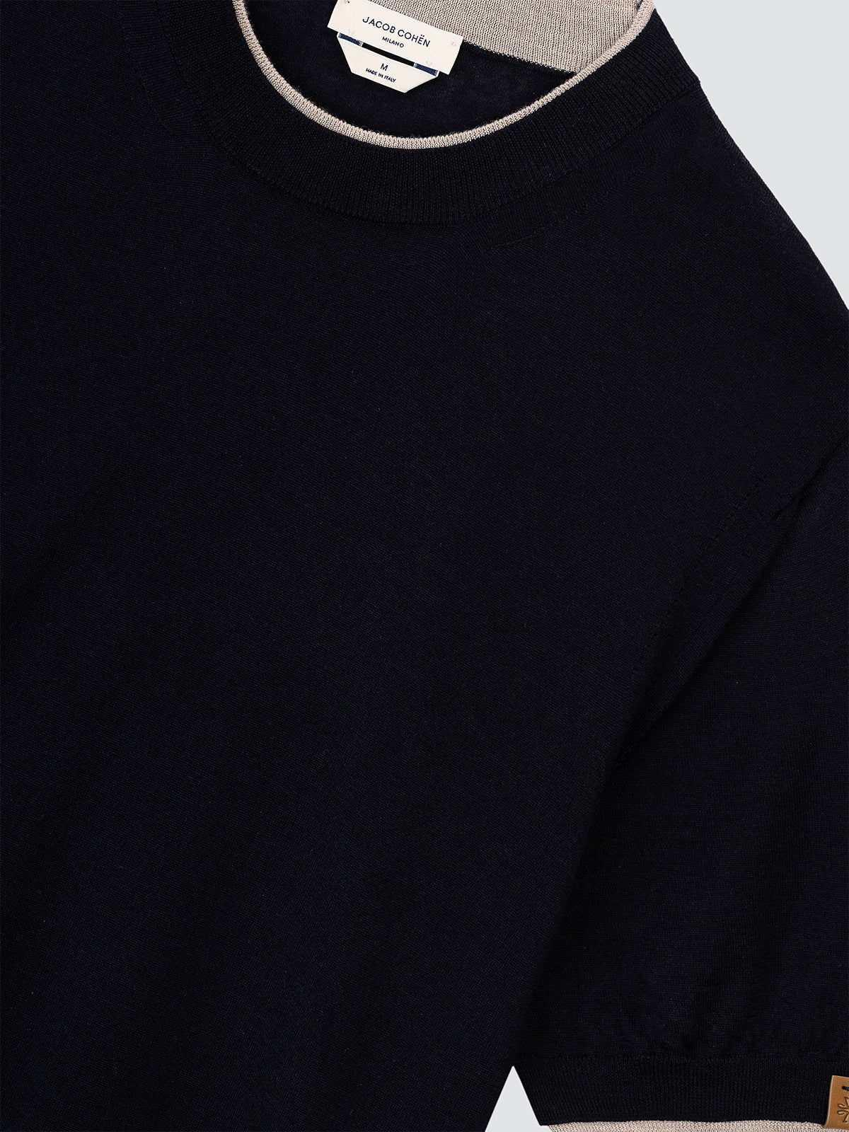 Navy sweater with beige trim on a light gray background