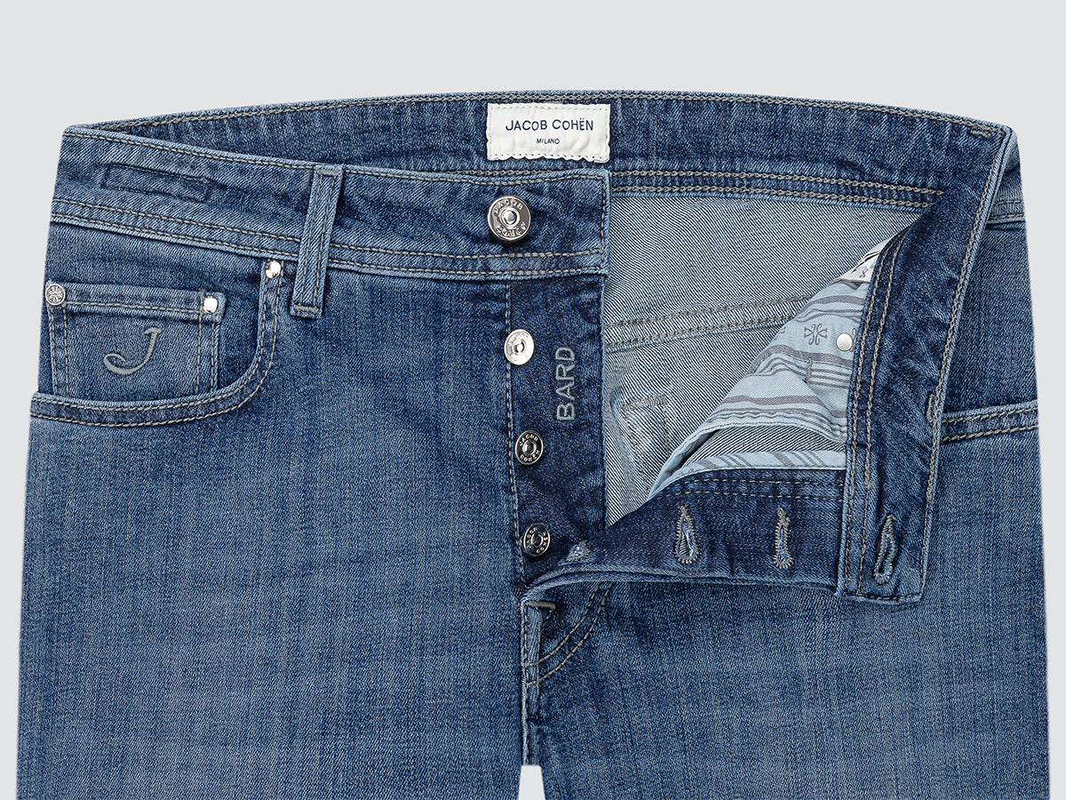 Close-up of blue jeans with visible branding on a light gray background