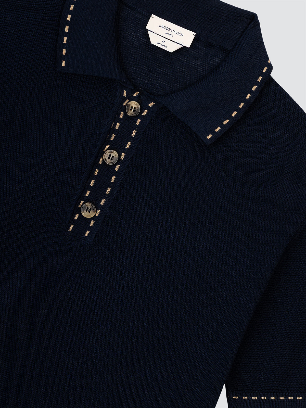 Navy blue polo with decorative buttons and stitching on a light gray background
