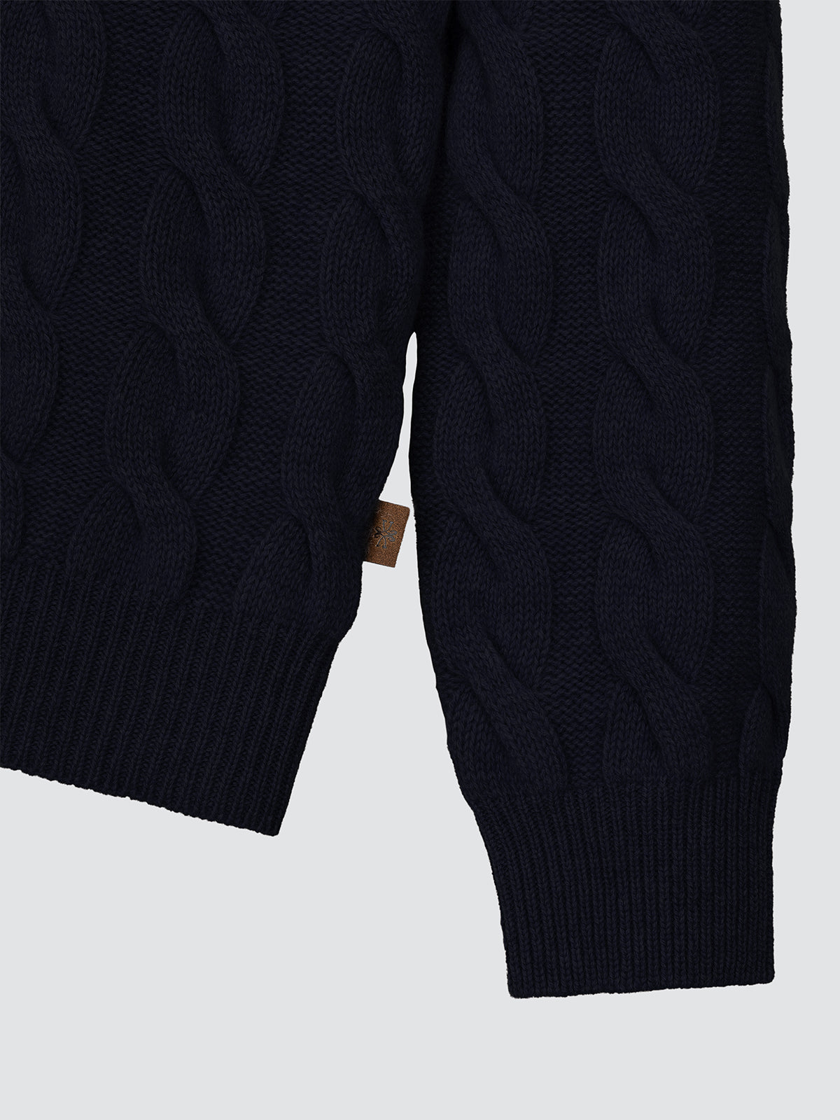 Close-up of a dark blue cable knit sweater on a light gray background