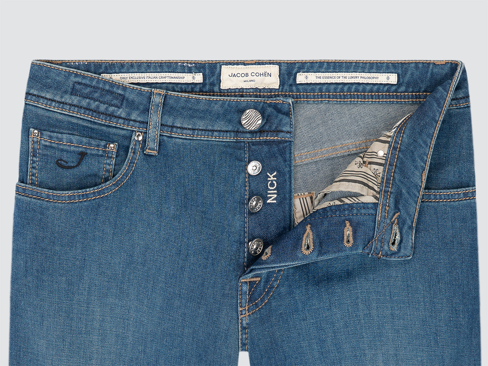 Close-up of blue jeans with brand label Jacob Cohen safari on a light gray background