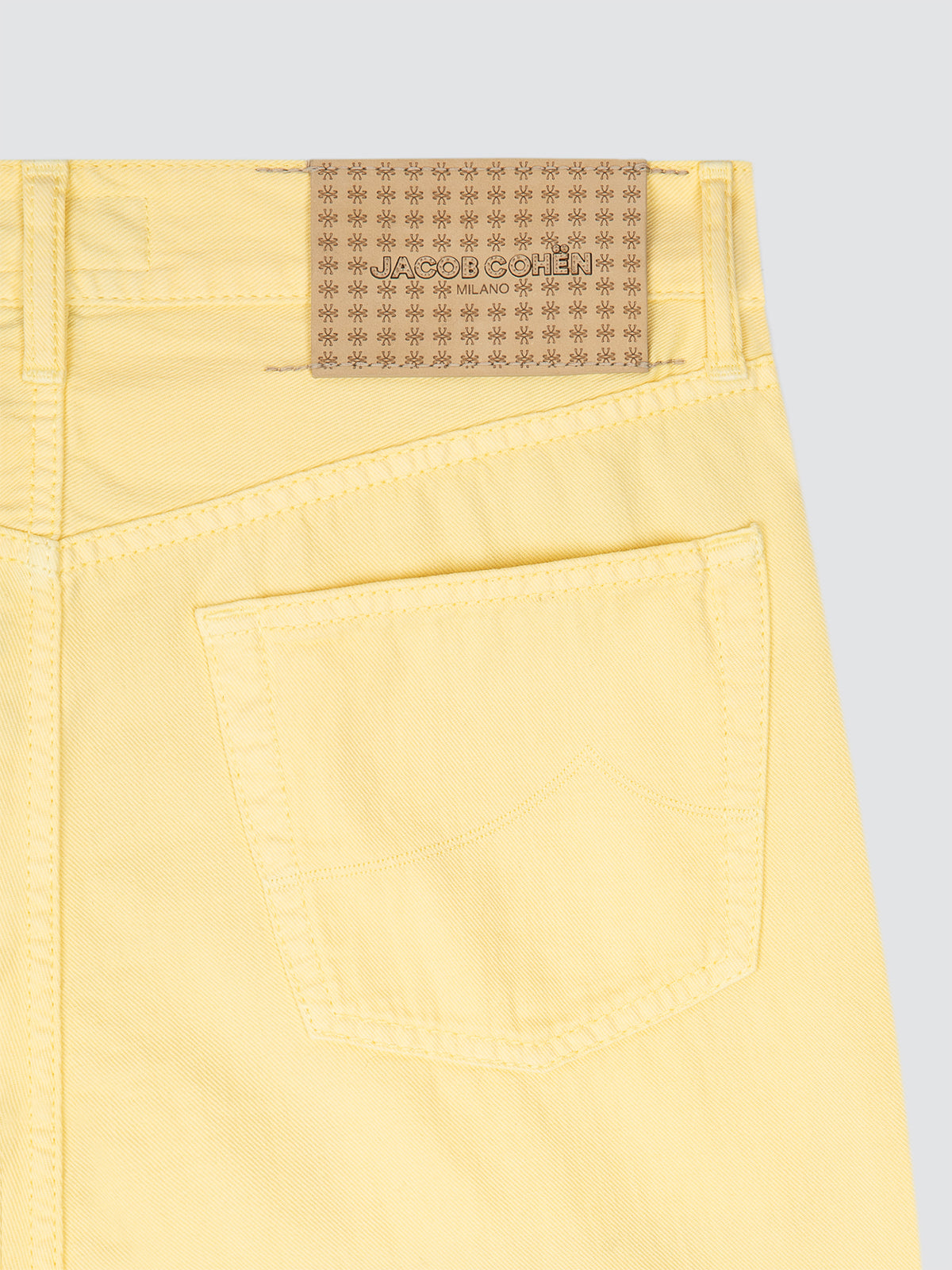Close-up of yellow pants with a brand label on a light gray background