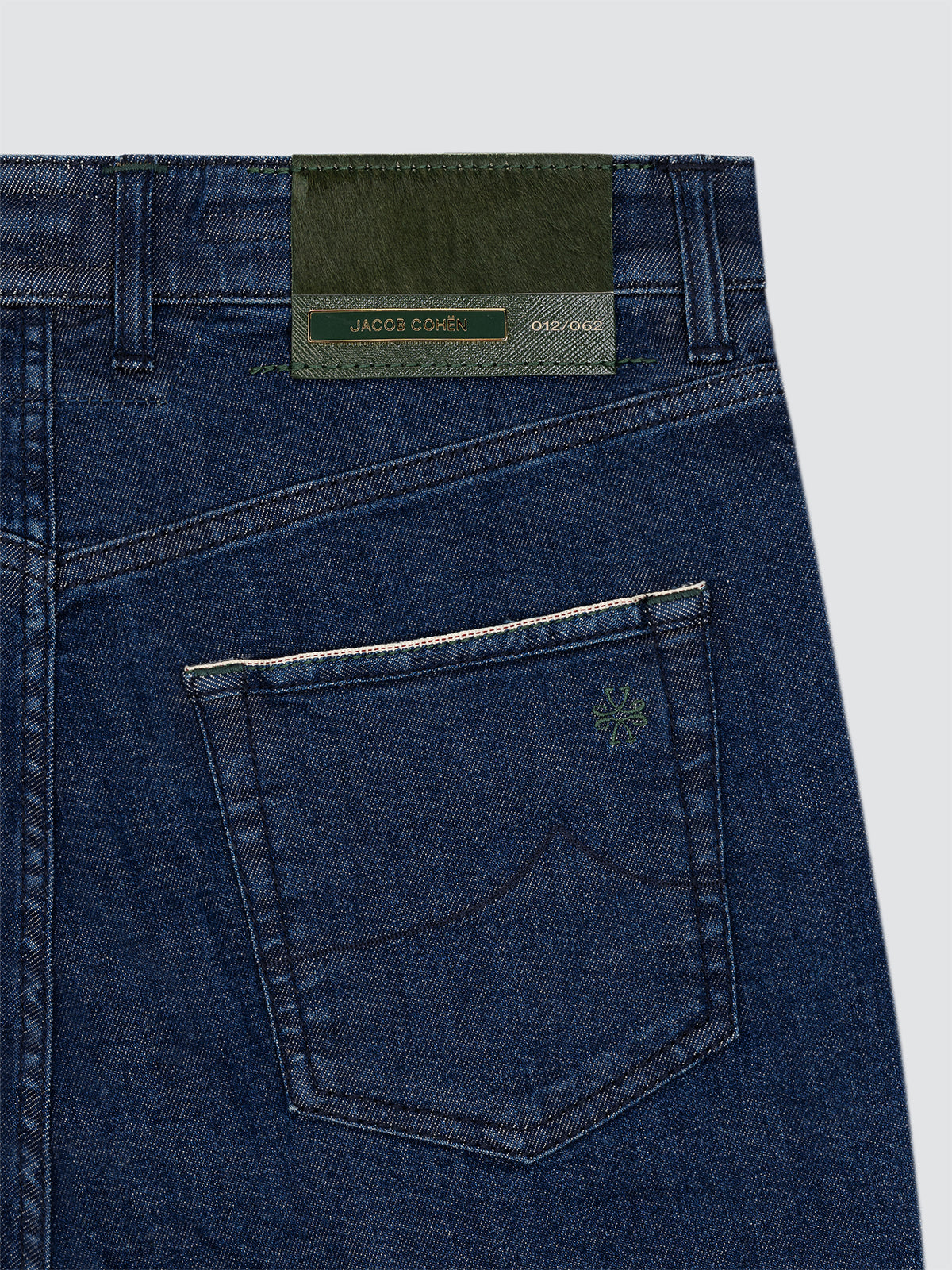 Close-up of blue limited Jacob Cohen Edo jeans with a brand label on a light gray background