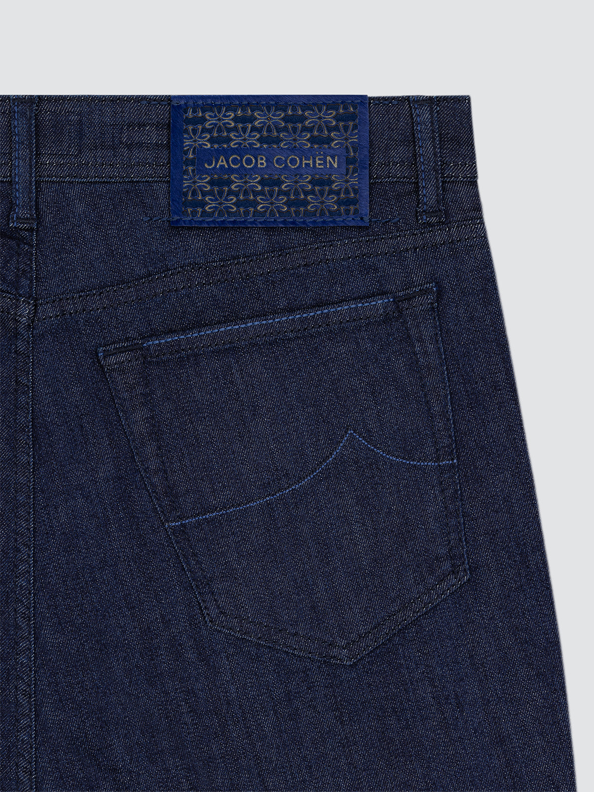 Navy blue denim jeans with a Jacob Cohen label on a light gray background