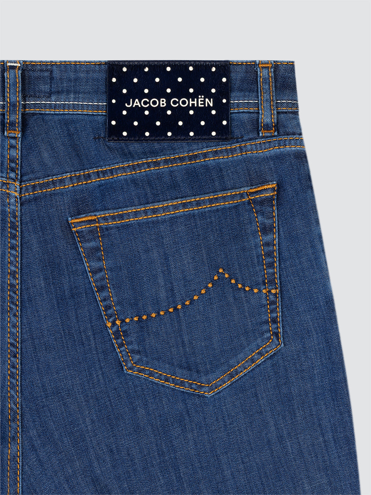 Close-up of blue jeans with a Jacob Cohen label POLKA DOTS on a light gray background