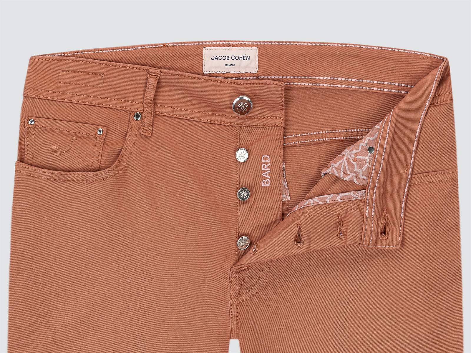 Dusty terracotta pants with visible branding Jacob Cohen on a light gray background