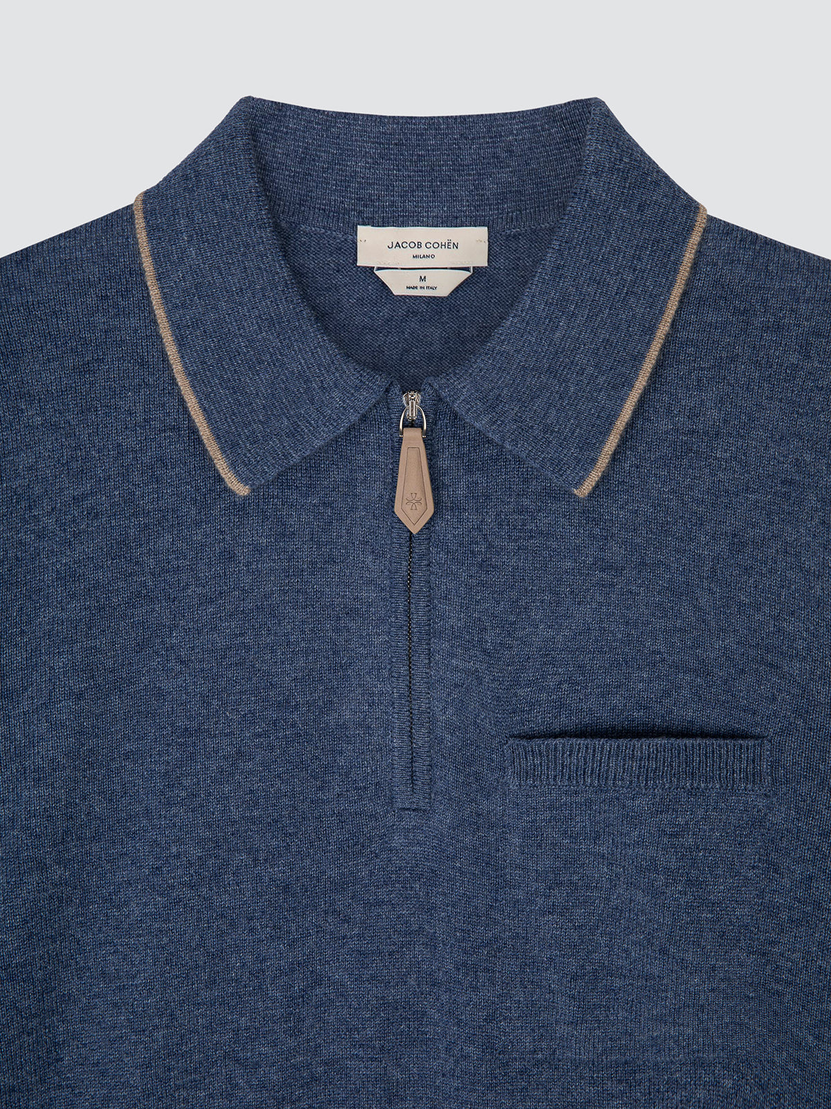 A close-up of a blue knit polo shirt by Jacob Cohen, featuring a half-zip collar with beige contrast piping and a beige zipper pull.