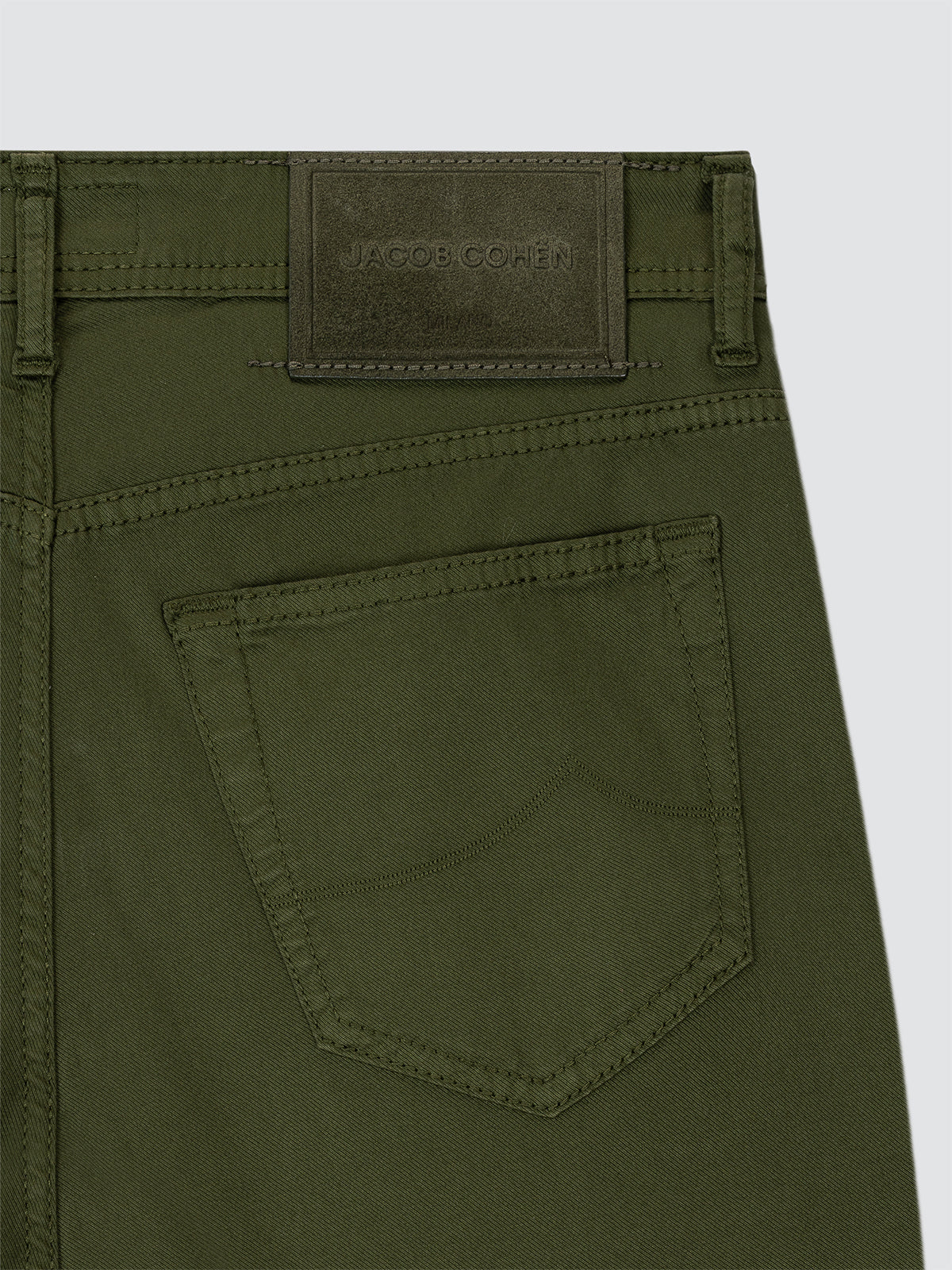 Close-up of green pants with a brand patch on a light gray background