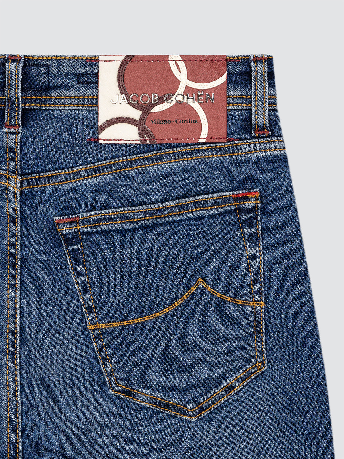 Close-up of blue jeans with a Jacob Cohen label olympic Milano Cortina on a gray background