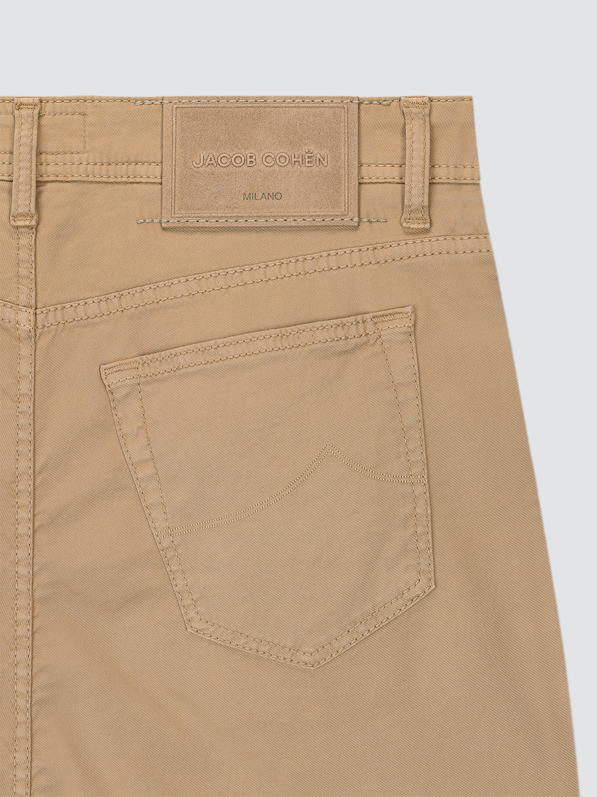 Beige pants with a brand label Jacob Cohen on a light gray background