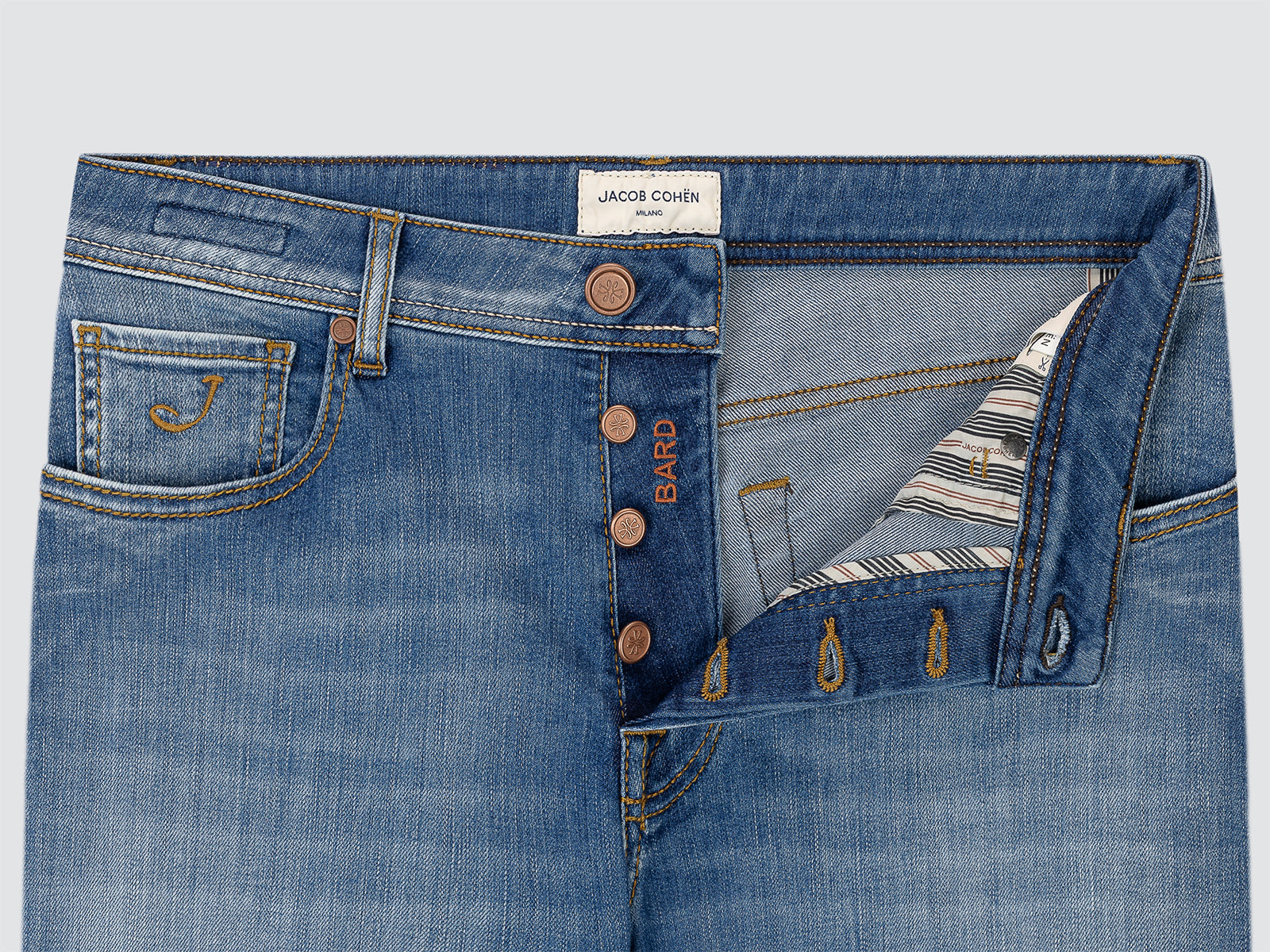 Close-up of blue jeans with a brand label on a light gray background