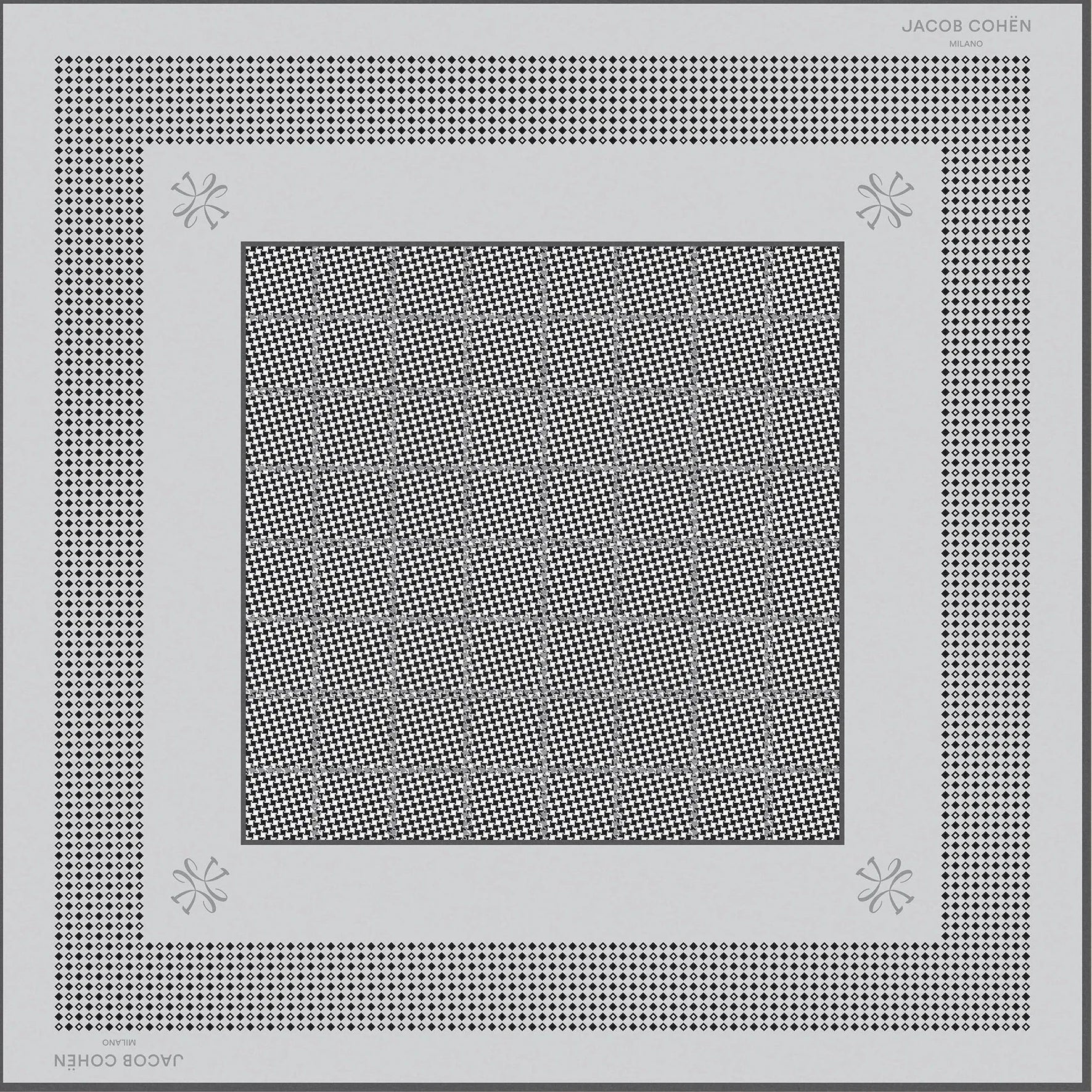 A square scarf with a geometric pattern, featuring a central gray patterned square surrounded by white and black patterned borders, displayed on a light beige background.