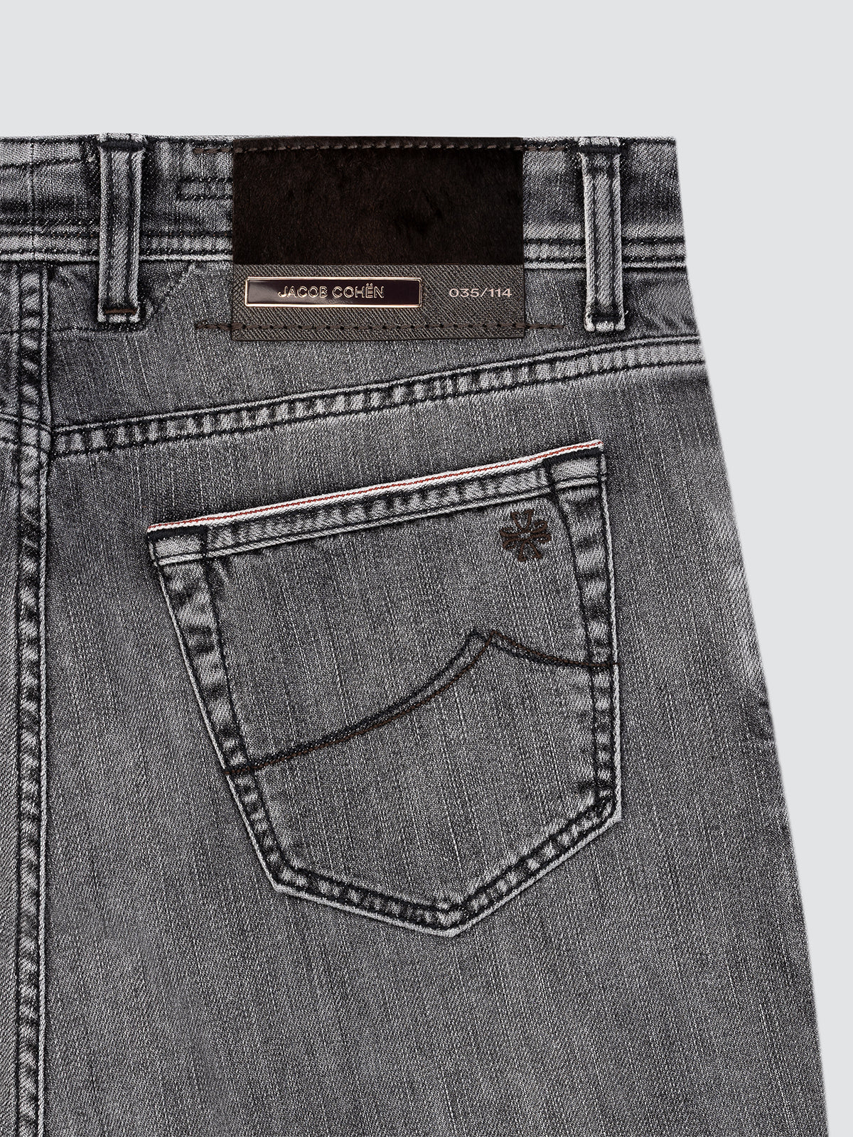 Close-up of gray jeans with a brand label limited edition Jacob Cohën on a light gray background