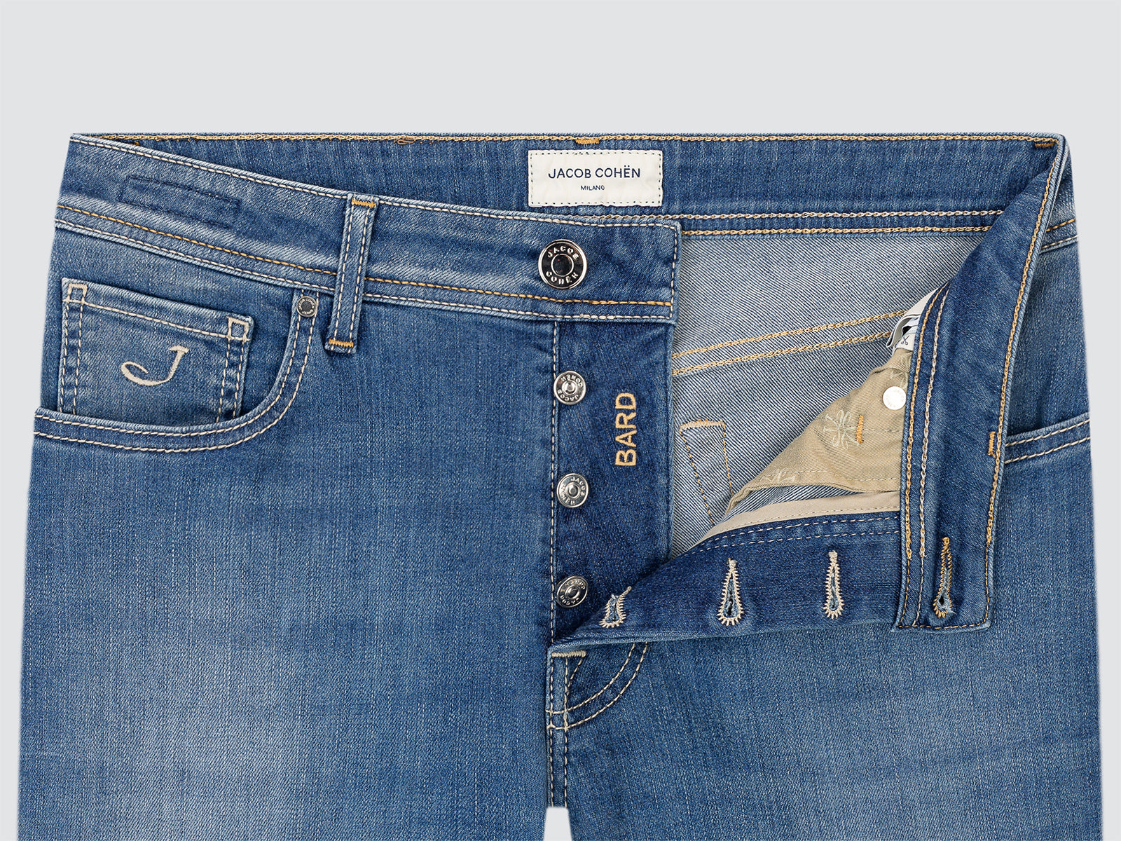 Close-up of blue jeans with visible branding Jacob Cohen on a light gray background
