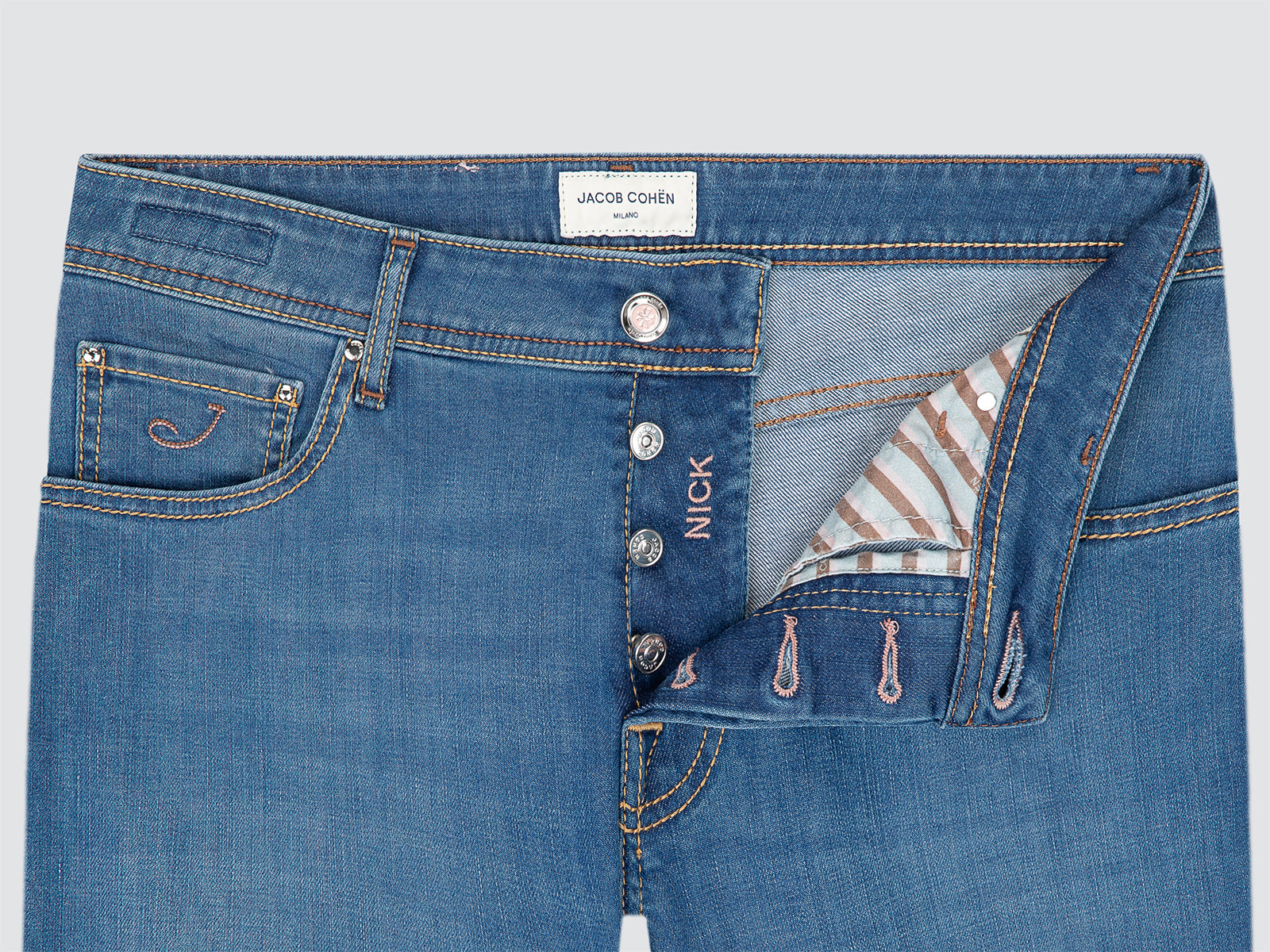 Close-up of blue jeans with brand label on a light gray background