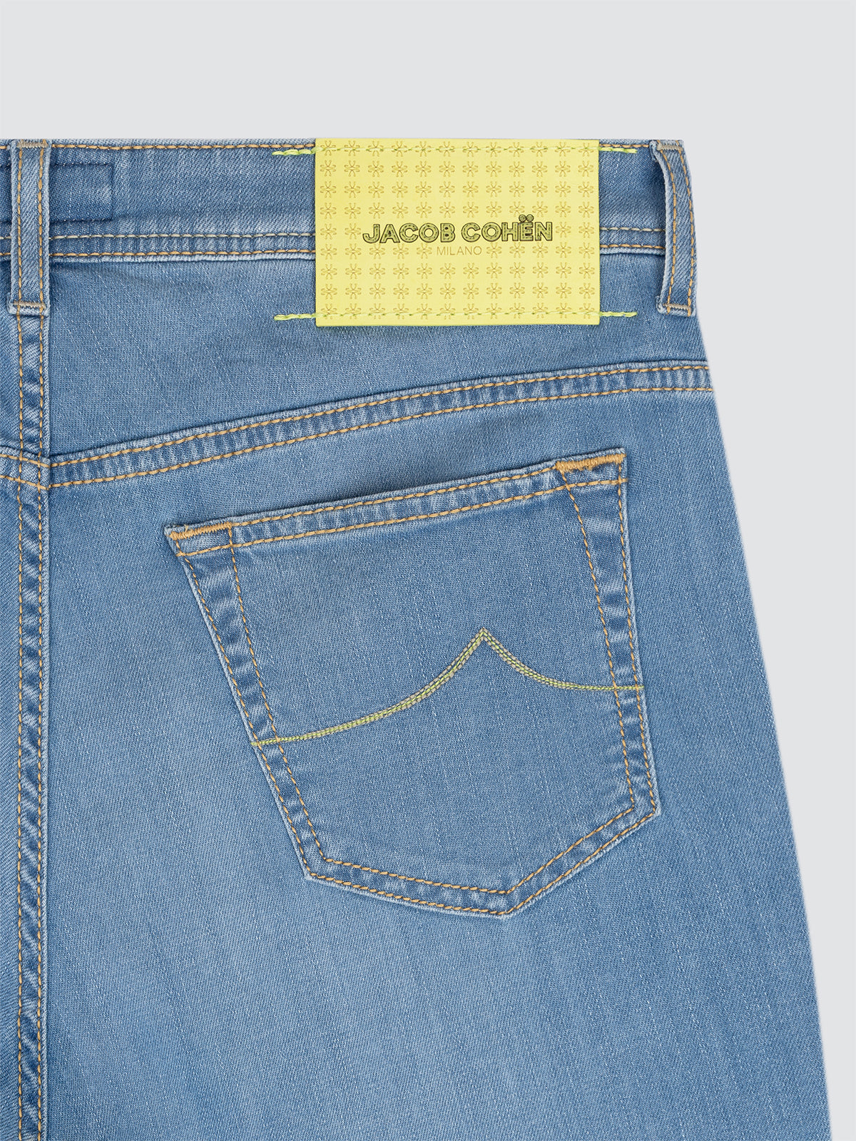 Close-up of blue BERMUDA DENIM Jacob Cohen with a yellow label on a light gray background