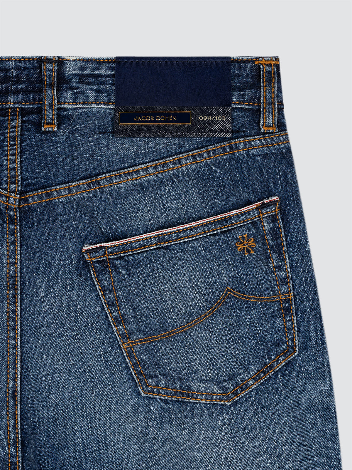 Close-up of blue jeans limited edition Jacob Cohen with a brand label on a light gray background