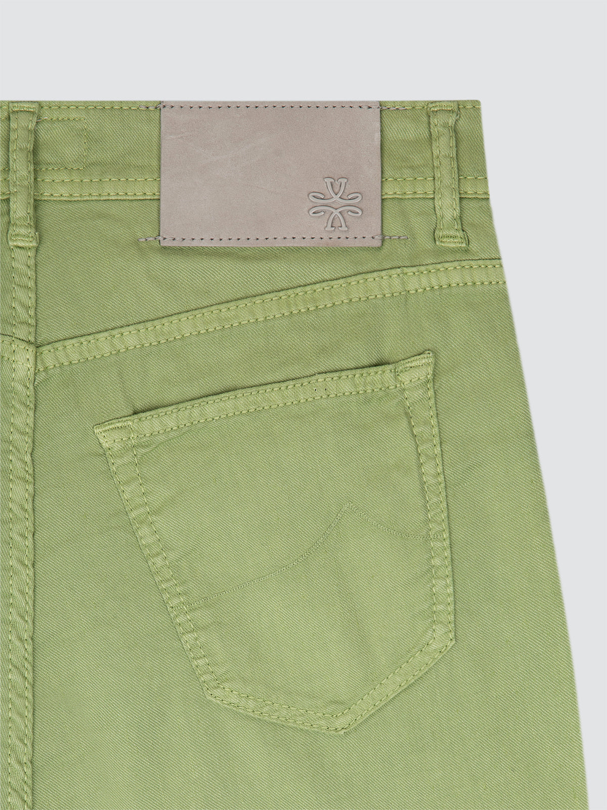 Close-up of green pants with a brand label on a white background