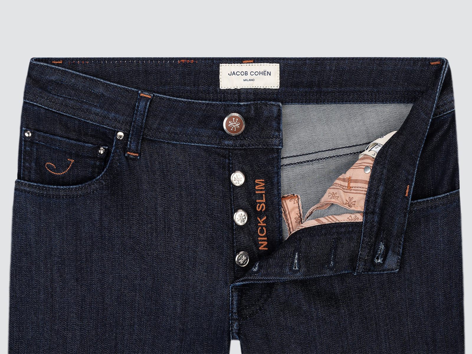 Dark blue jeans with visible brand Jacob Cohen Milano label on a light gray background