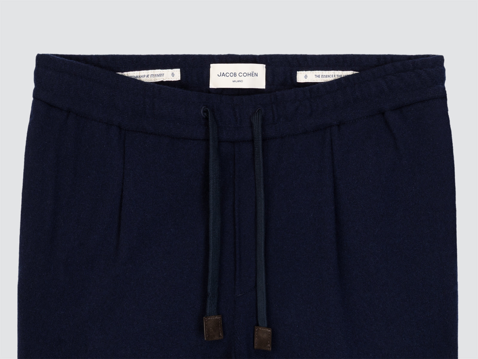 Navy blue cashmere pants with drawstring and brand label on a light gray background