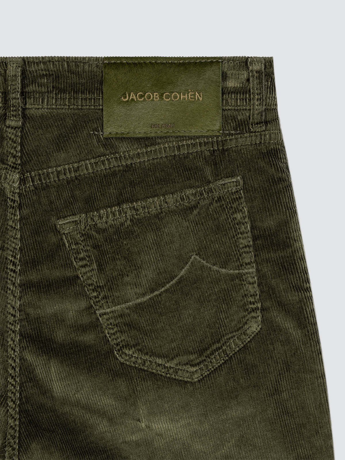 Close-up of green corduroy pants with a Jacob Cohen label on a white background