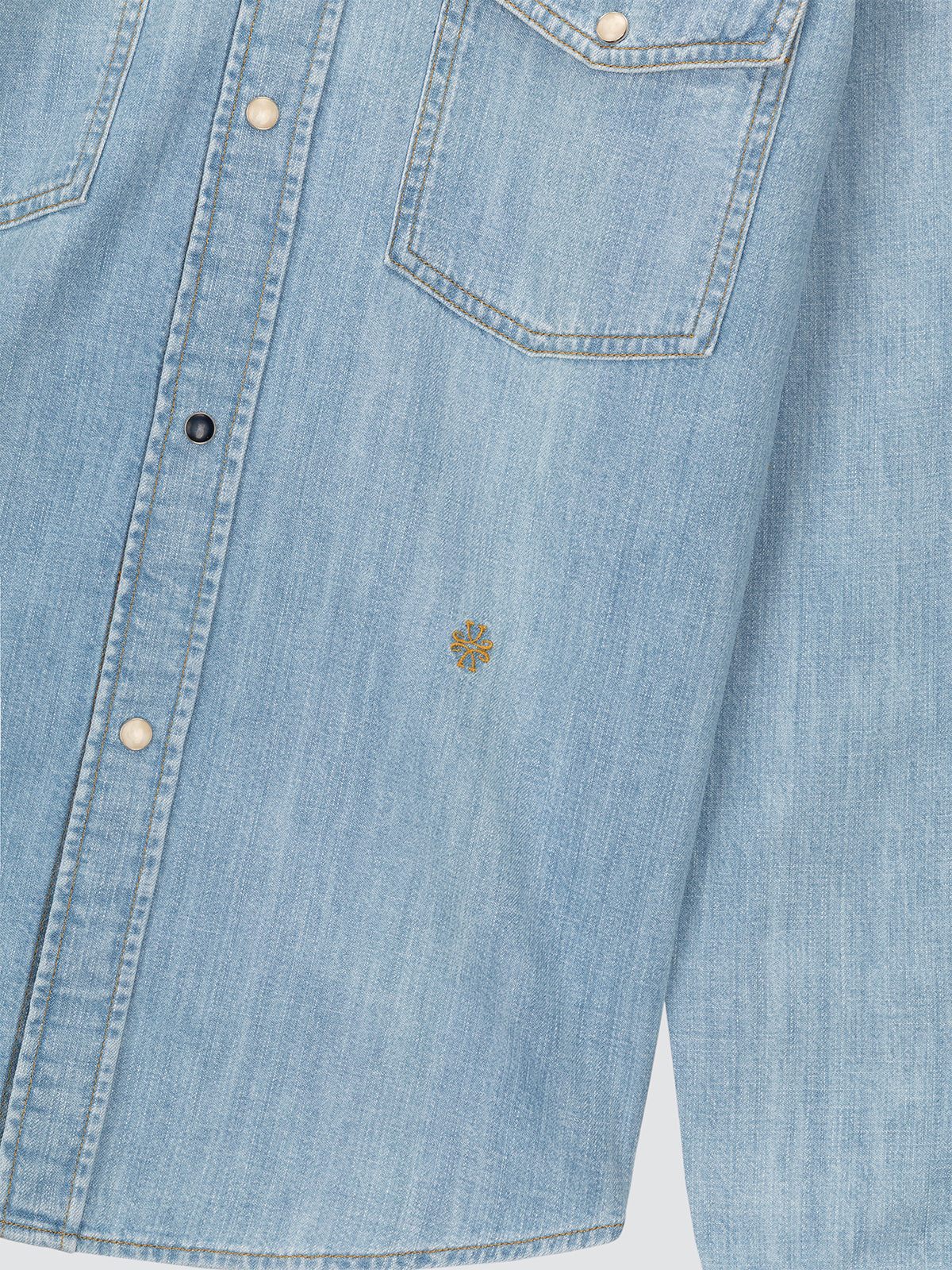 Close-up of a light blue denim shirt with buttons and a pocket.