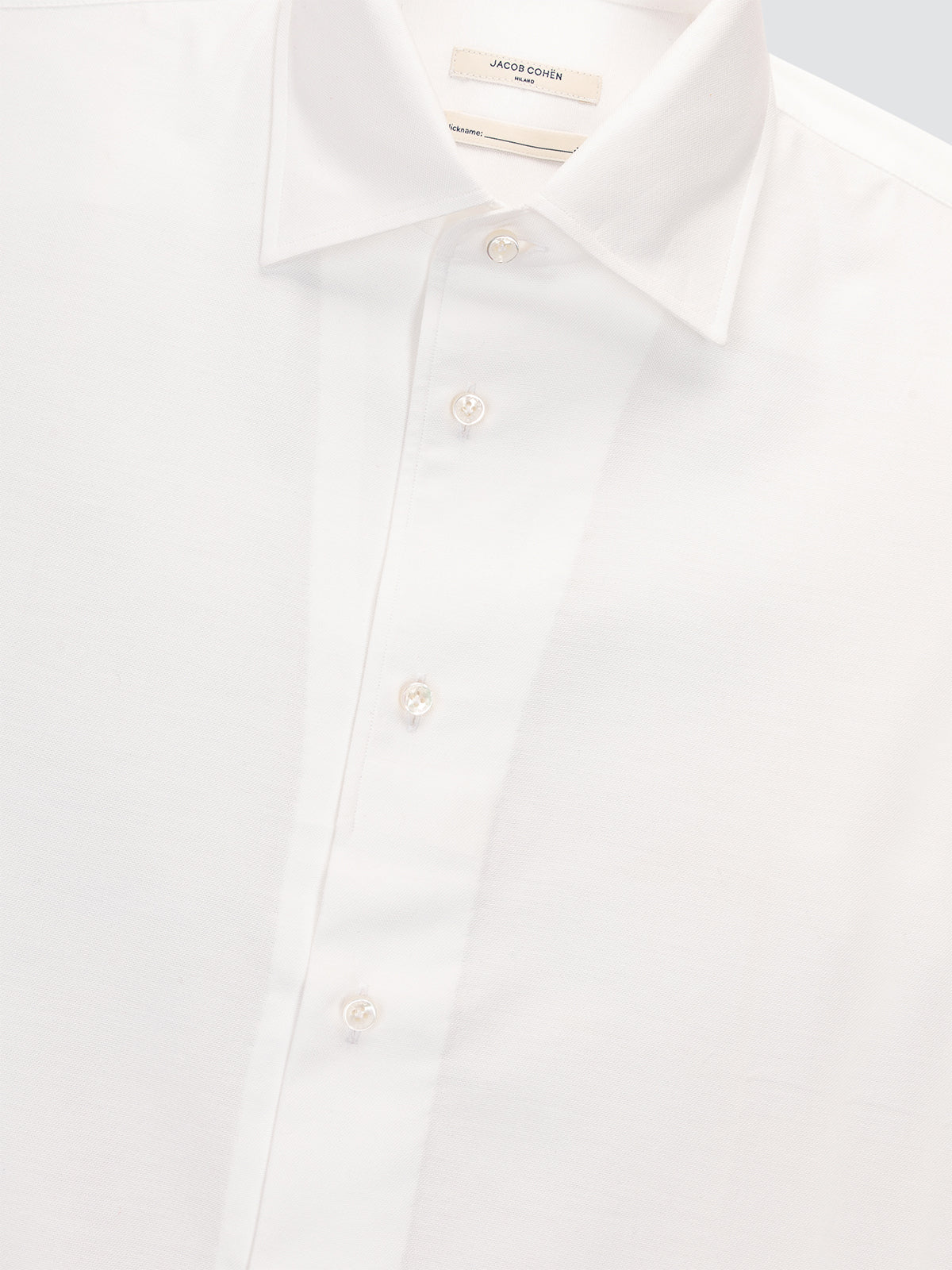White dress shirt with a close-up of the collar and buttons on a light gray background.