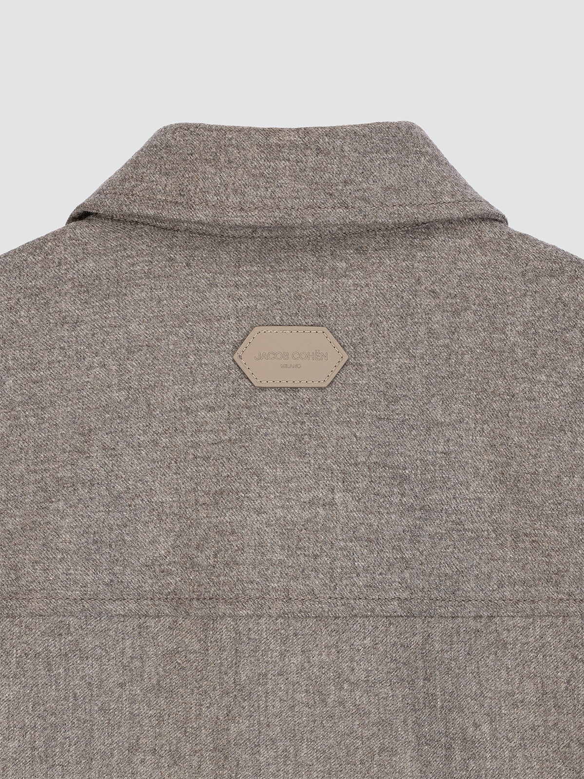 Gray beige jacket with a brand logo on the back against a light gray background