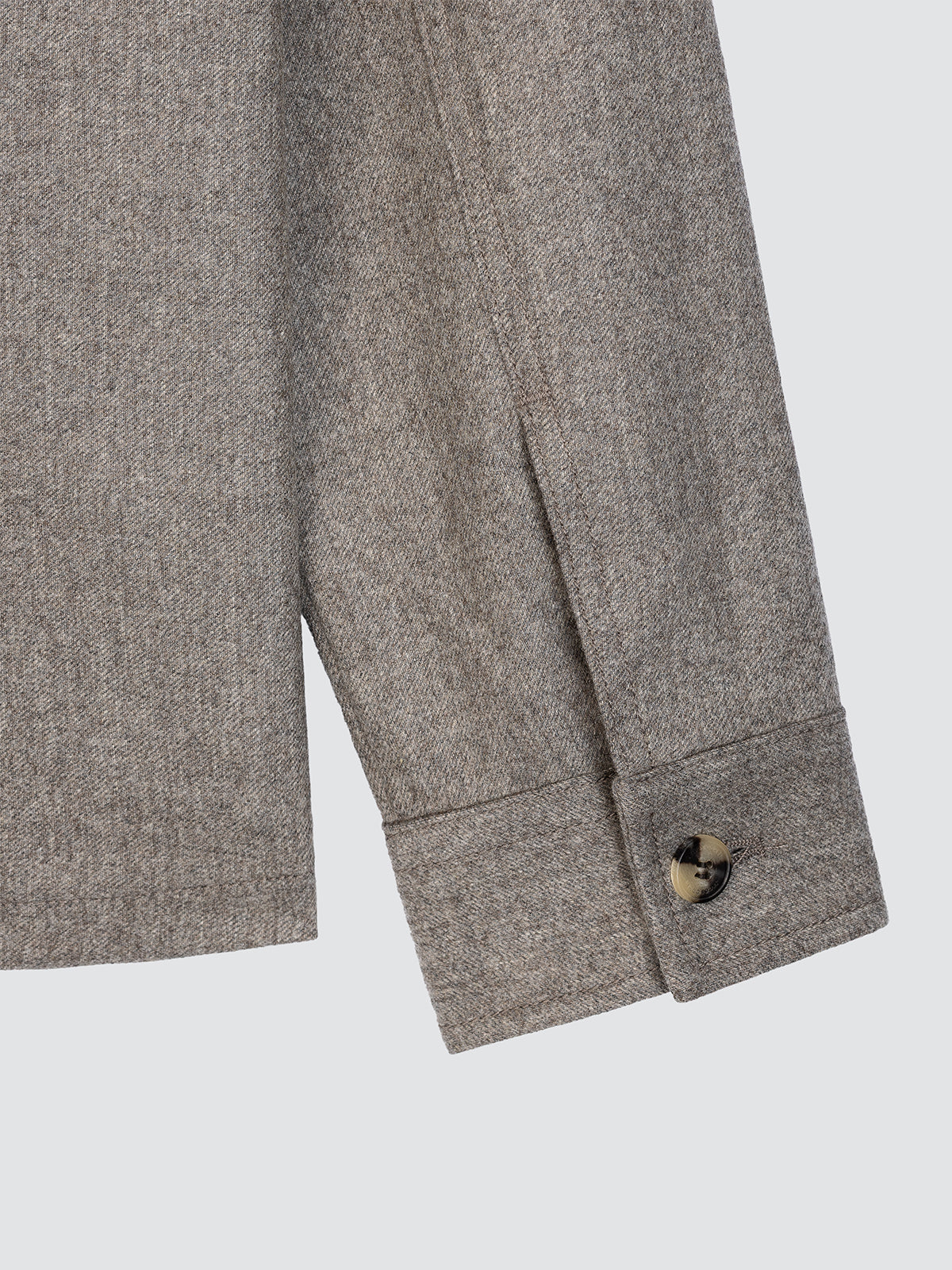 Close-up of a gray beige textured fabric with a button on a white background