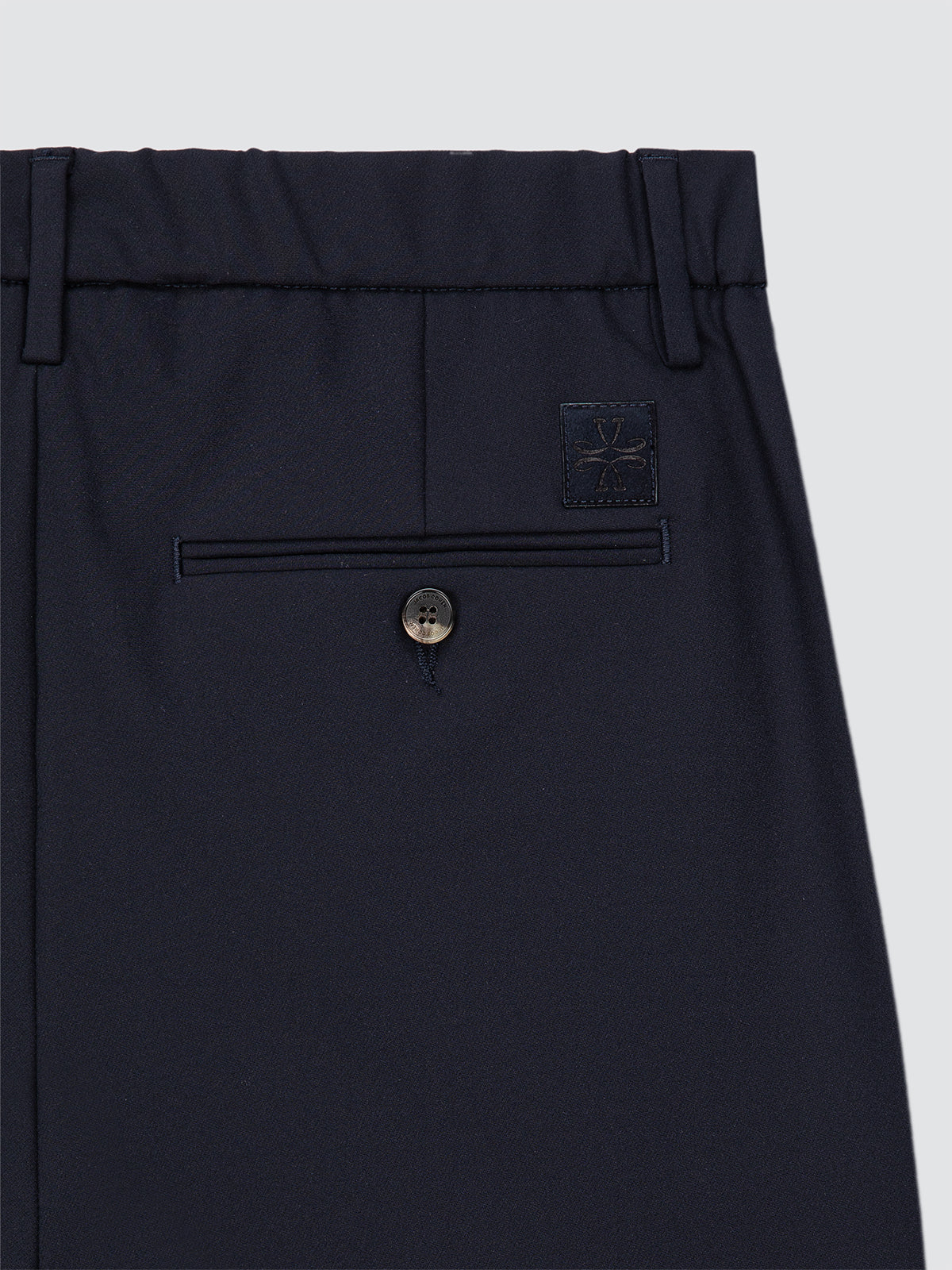 Navy blue pants with a button and a brand logo on a light gray background