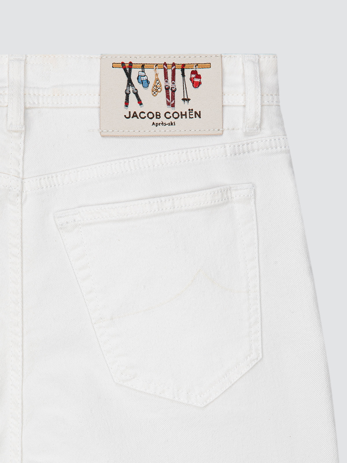 Close-up of a white garment with a Jacob Cohen label pares ski on a light gray background